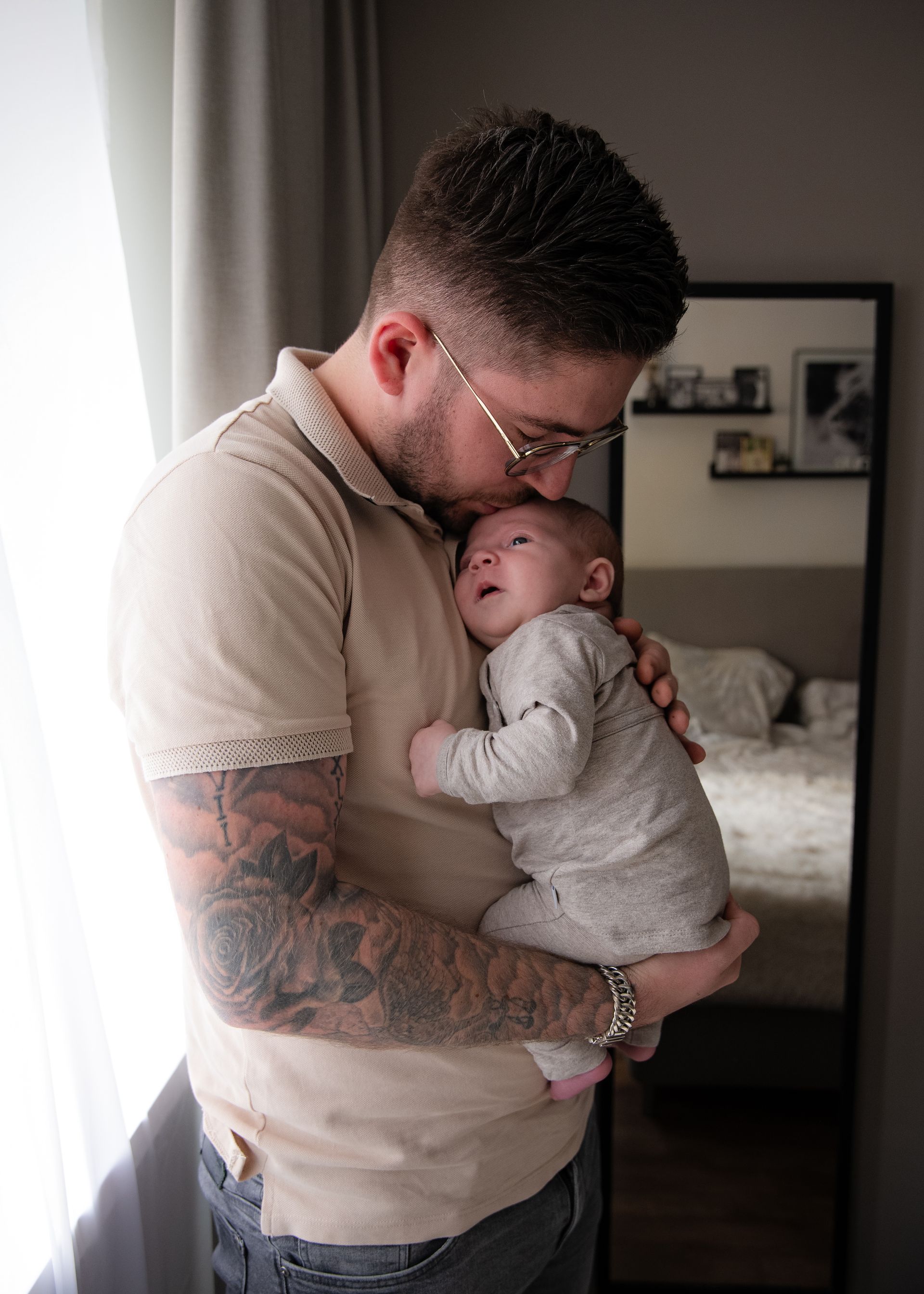 Een man houdt een baby in zijn armen voor een spiegel.