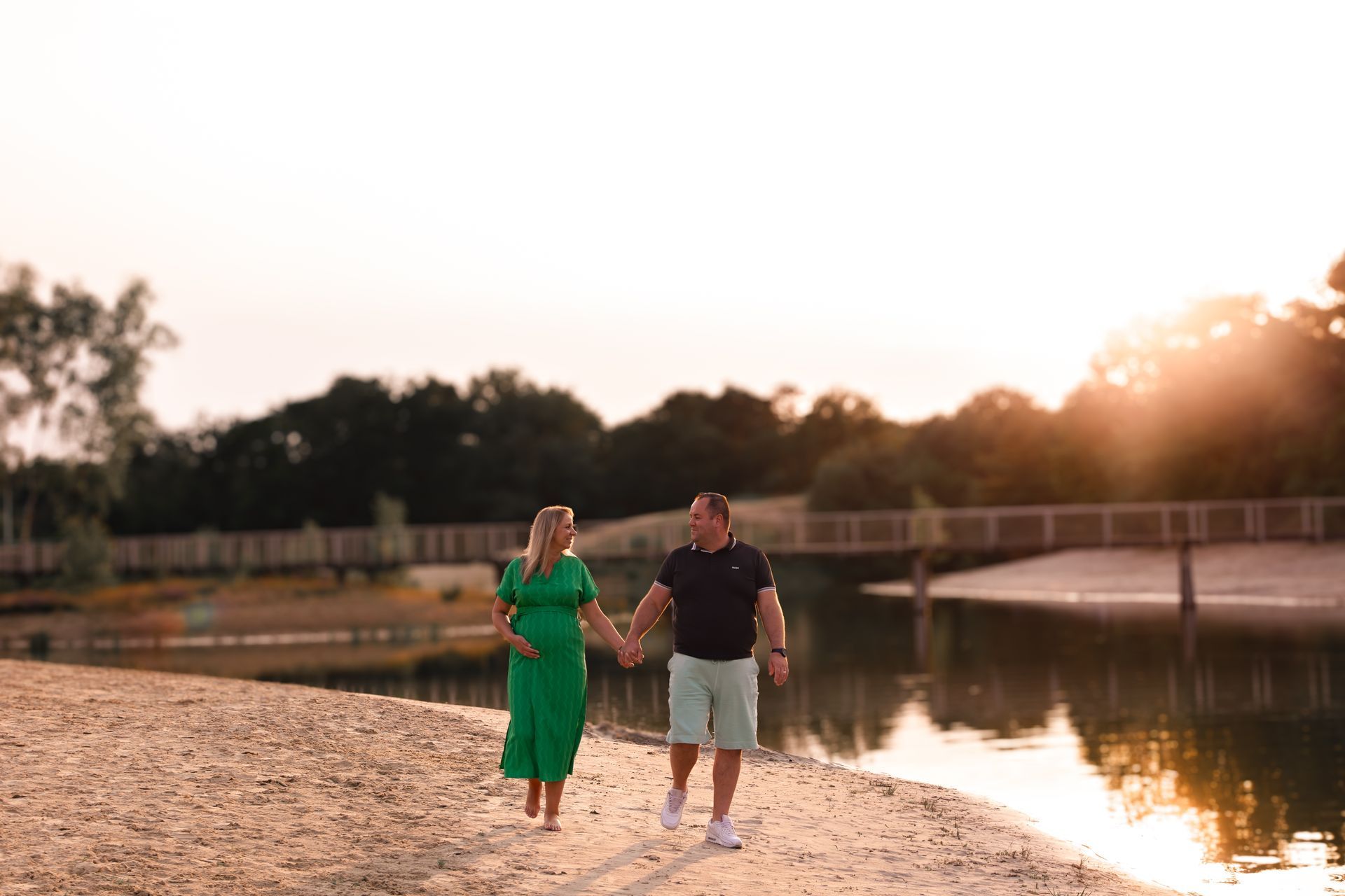 Een man en een vrouw lopen hand in hand over het strand.