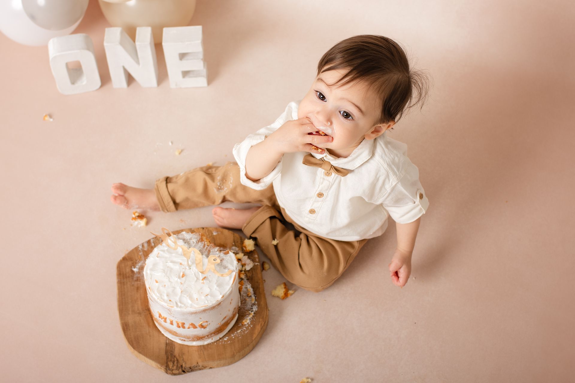Een baby zit op de grond en eet een taart.