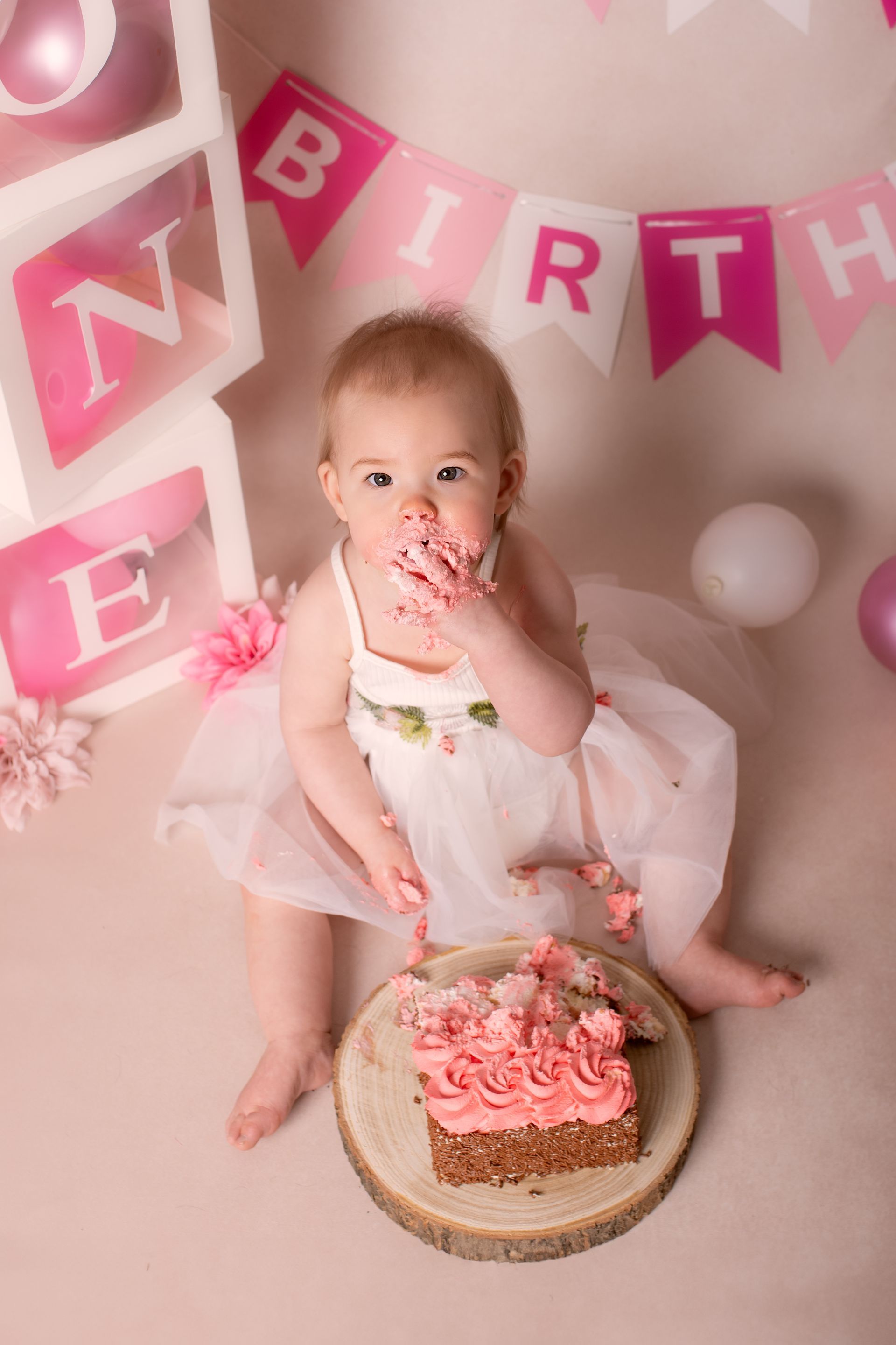 Een babymeisje zit op de grond en eet een taart.