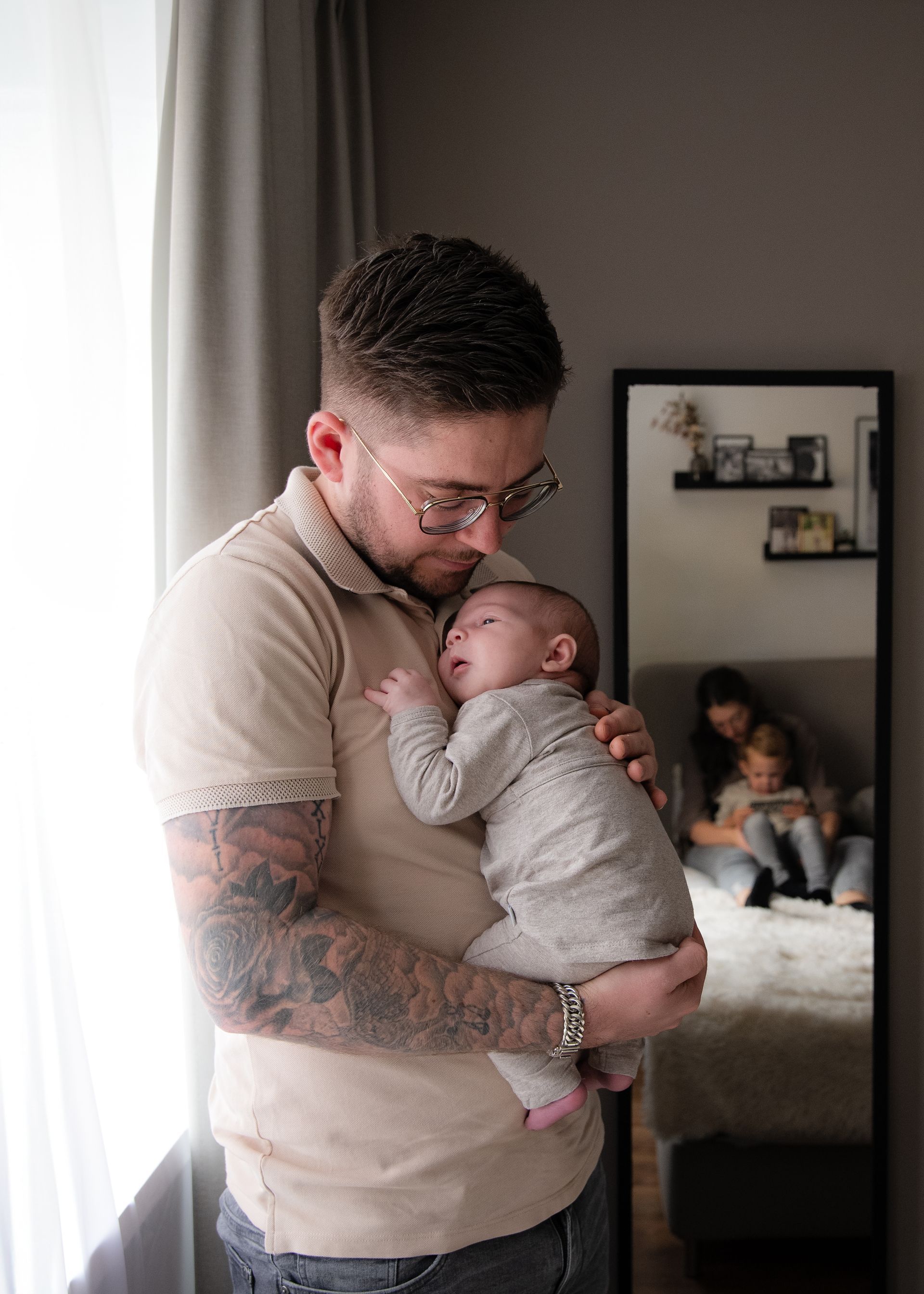 Een man houdt een baby in zijn armen voor een spiegel.