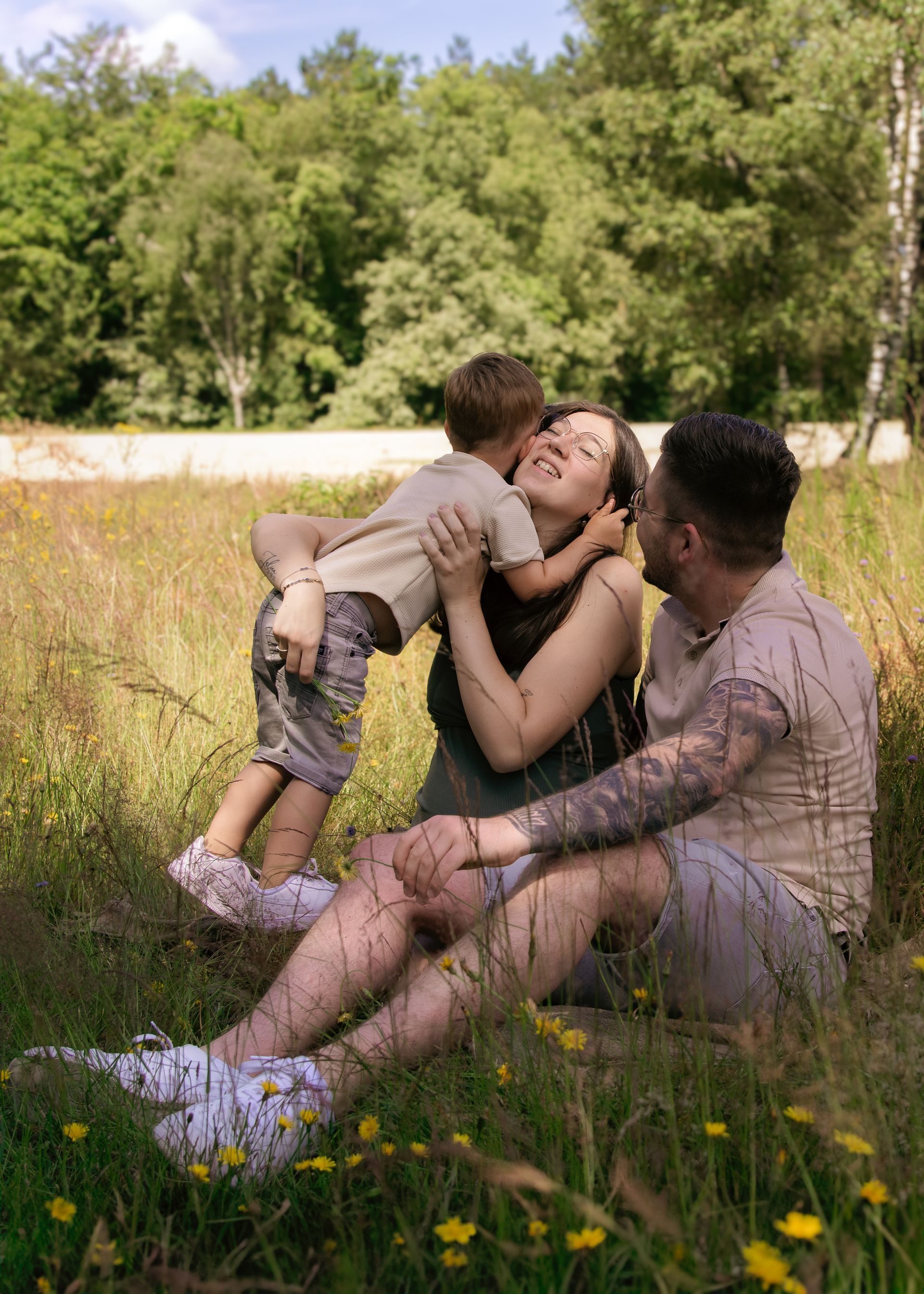 Een man en een vrouw zitten in een veld met een kind in hun armen.