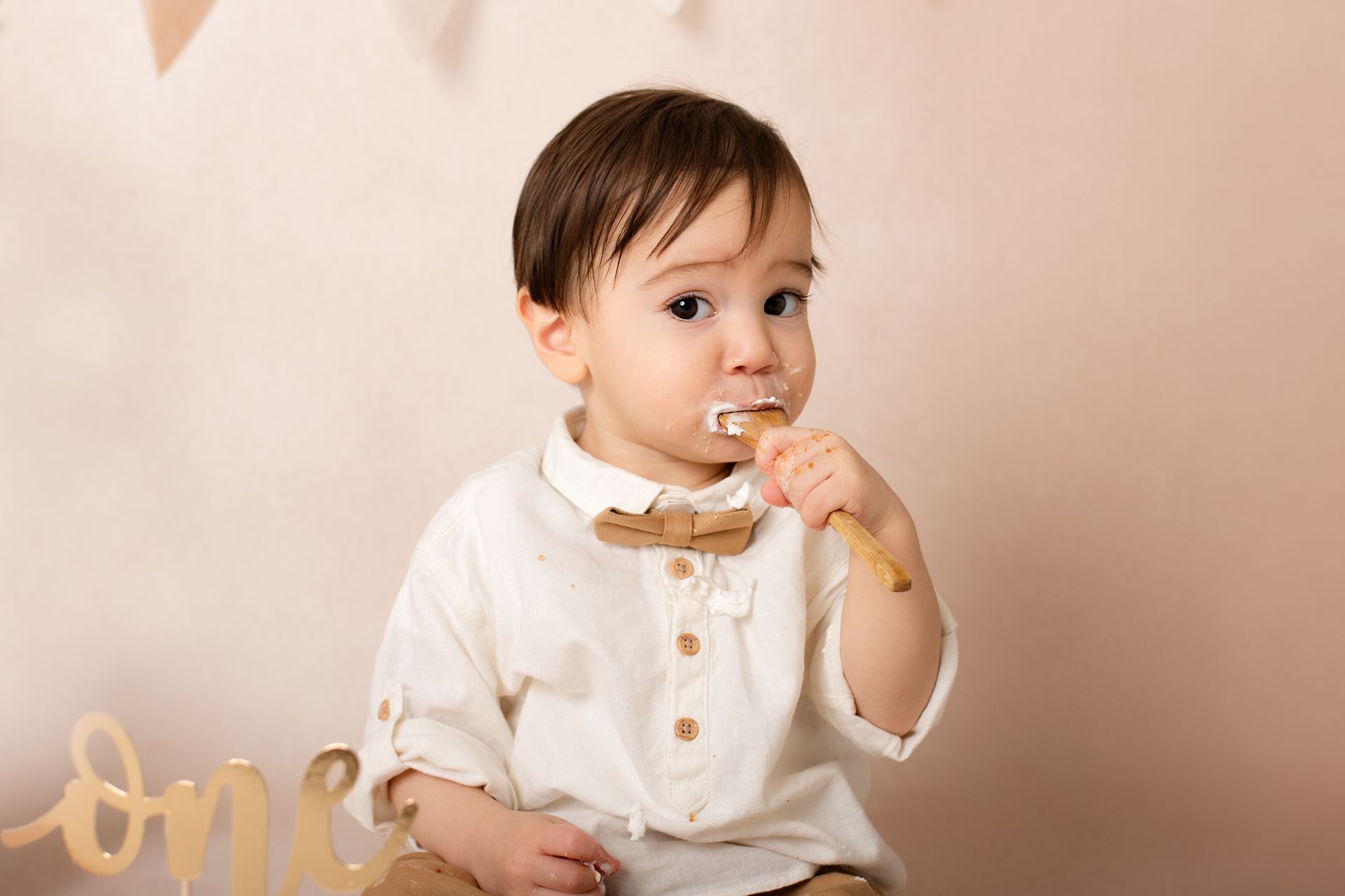 Een baby eet een stuk taart met een lepel.