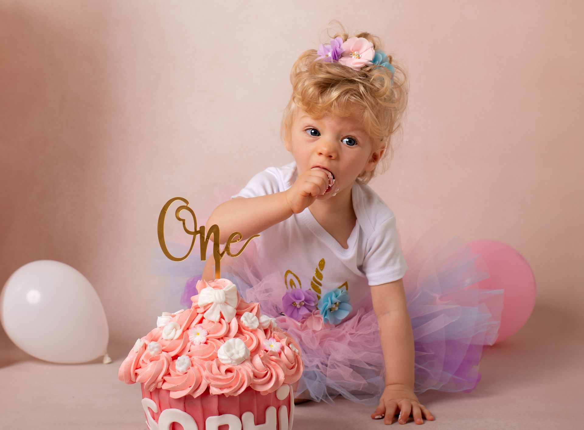 Een klein meisje eet een gigantische cupcake voor haar eerste verjaardag.