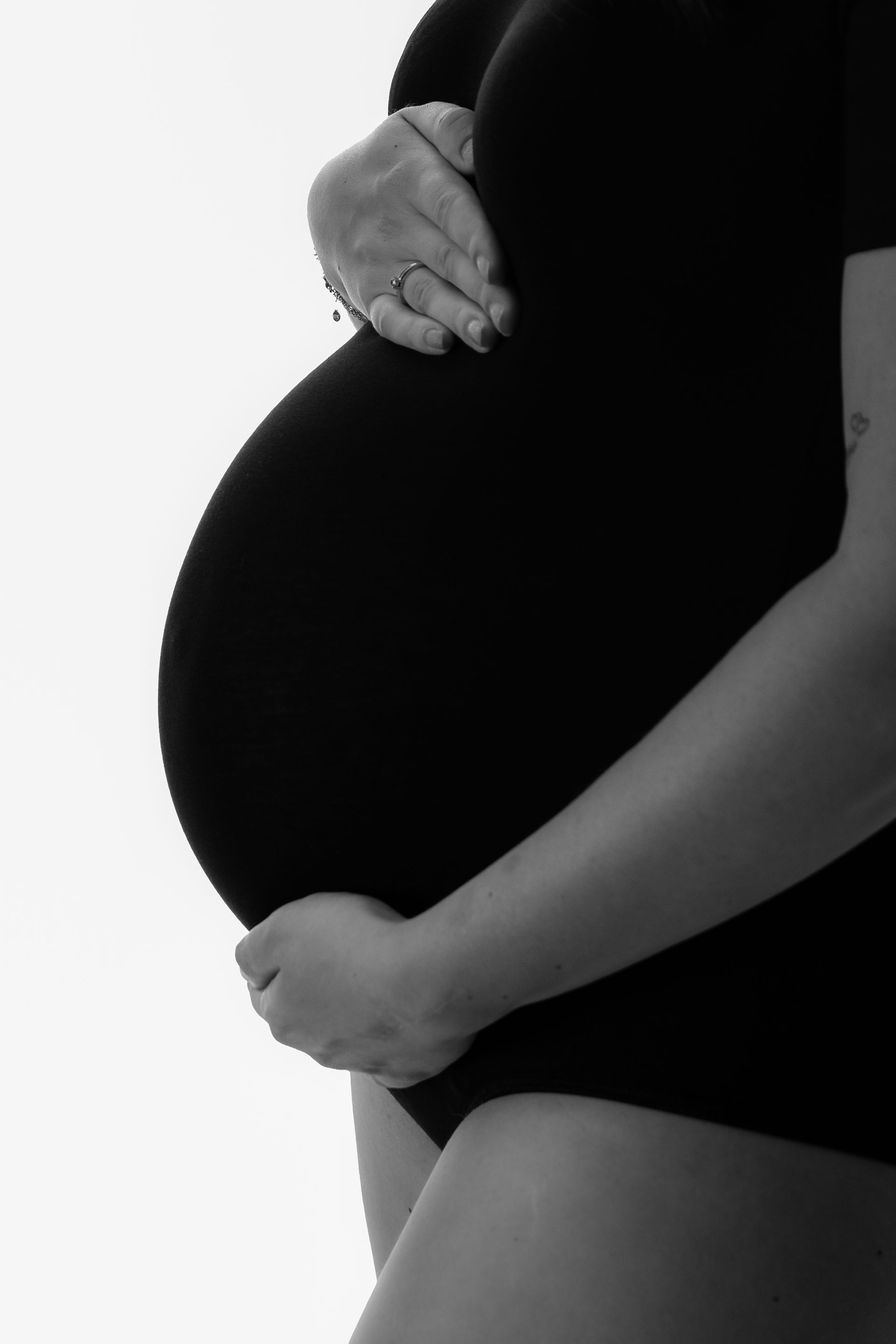 Een zwart-witfoto van een zwangere vrouw die haar buik vasthoudt.