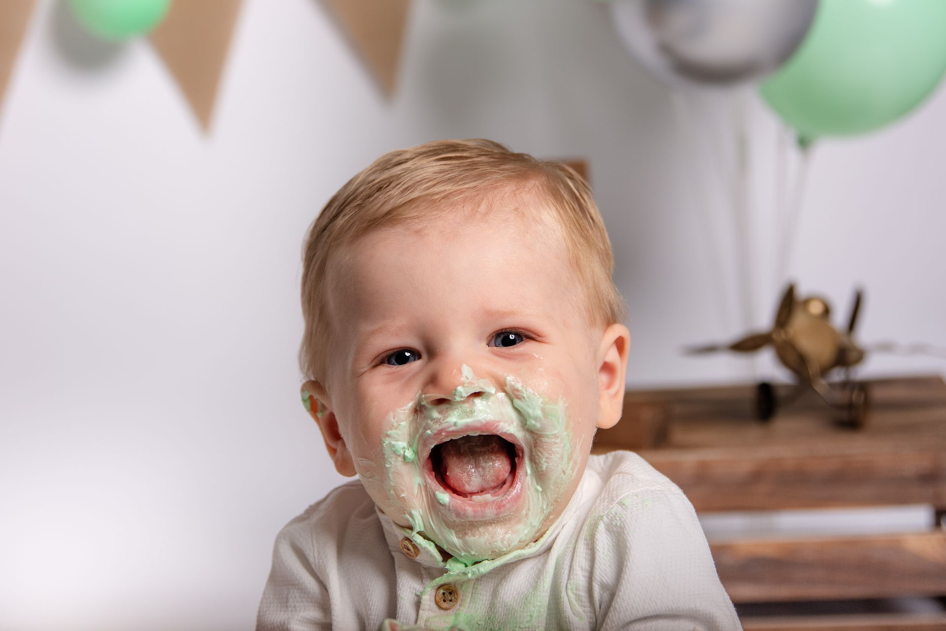 Een baby met glazuur op zijn gezicht zit op een tafel.