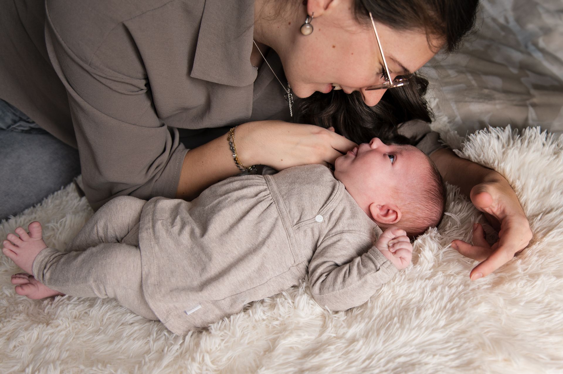 Een vrouw ligt met een baby op bed.
