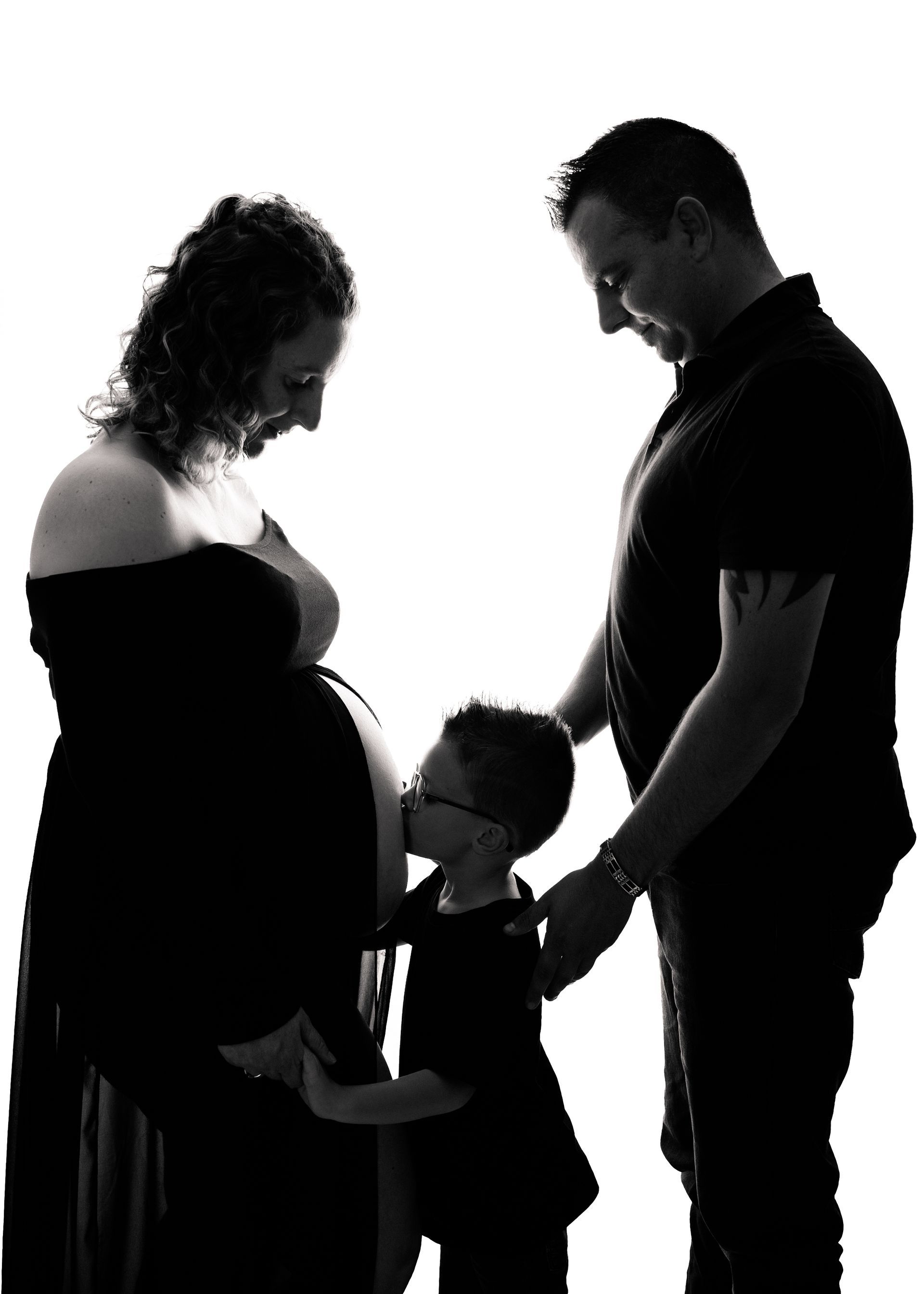 Een zwangere vrouw staat naast een man en een kind.