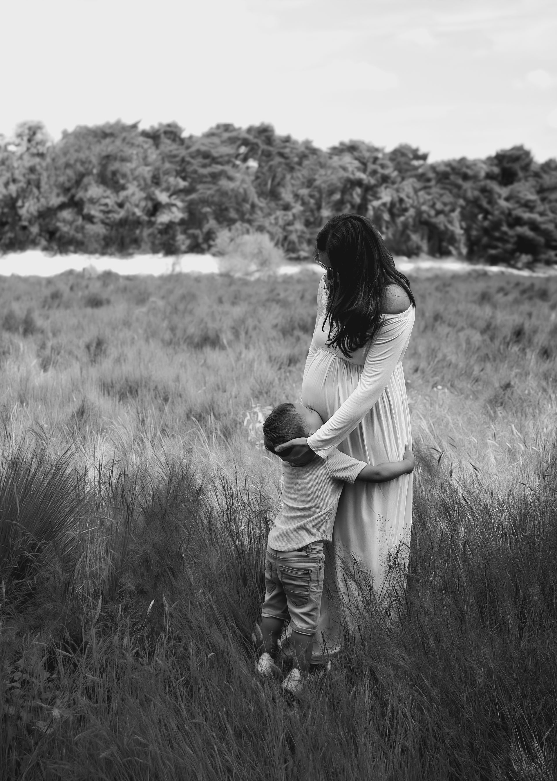 Op een zwart-witfoto houdt een vrouw een kind vast in een veld.