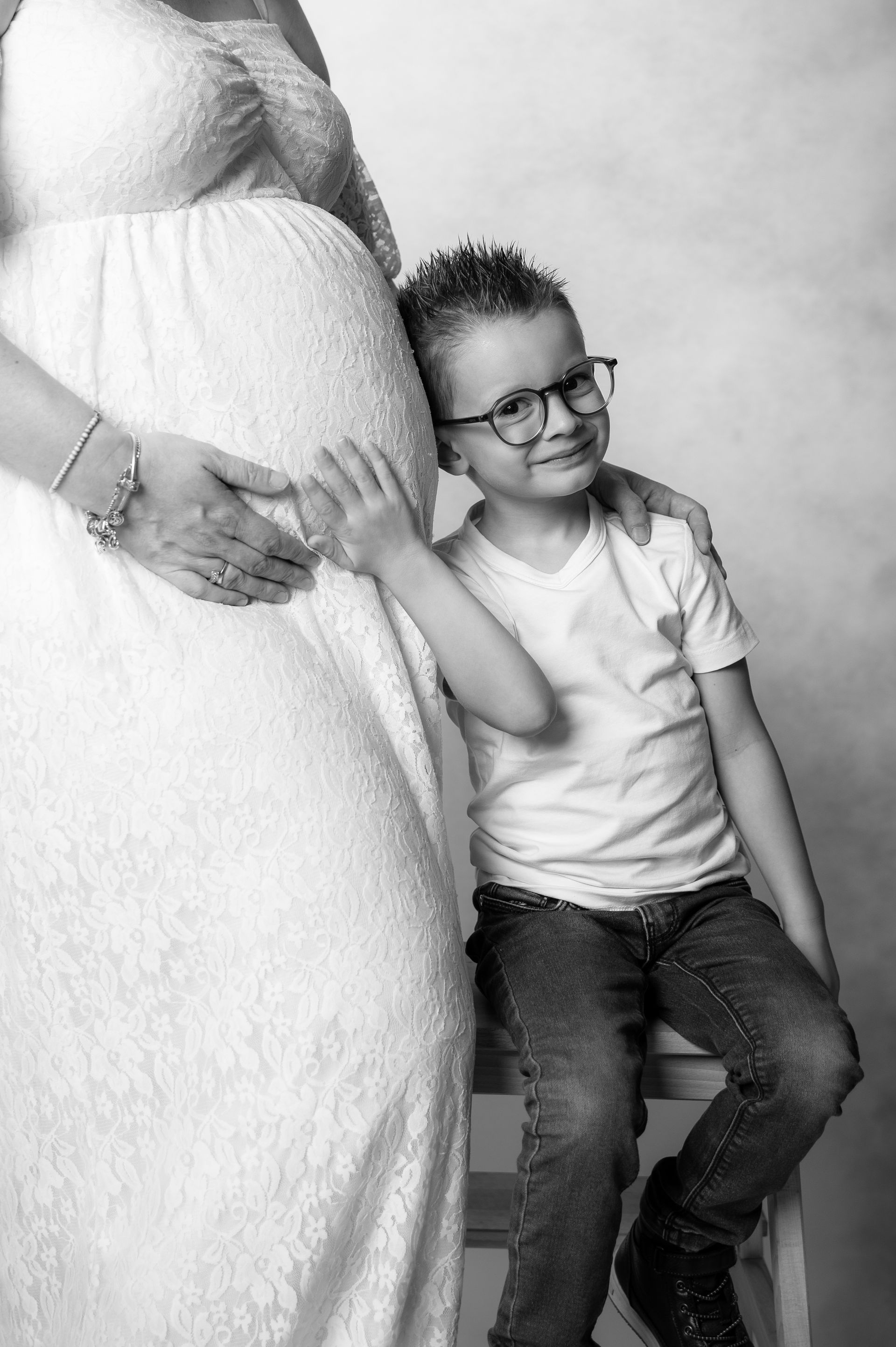 Een jongen zit naast een zwangere vrouw.