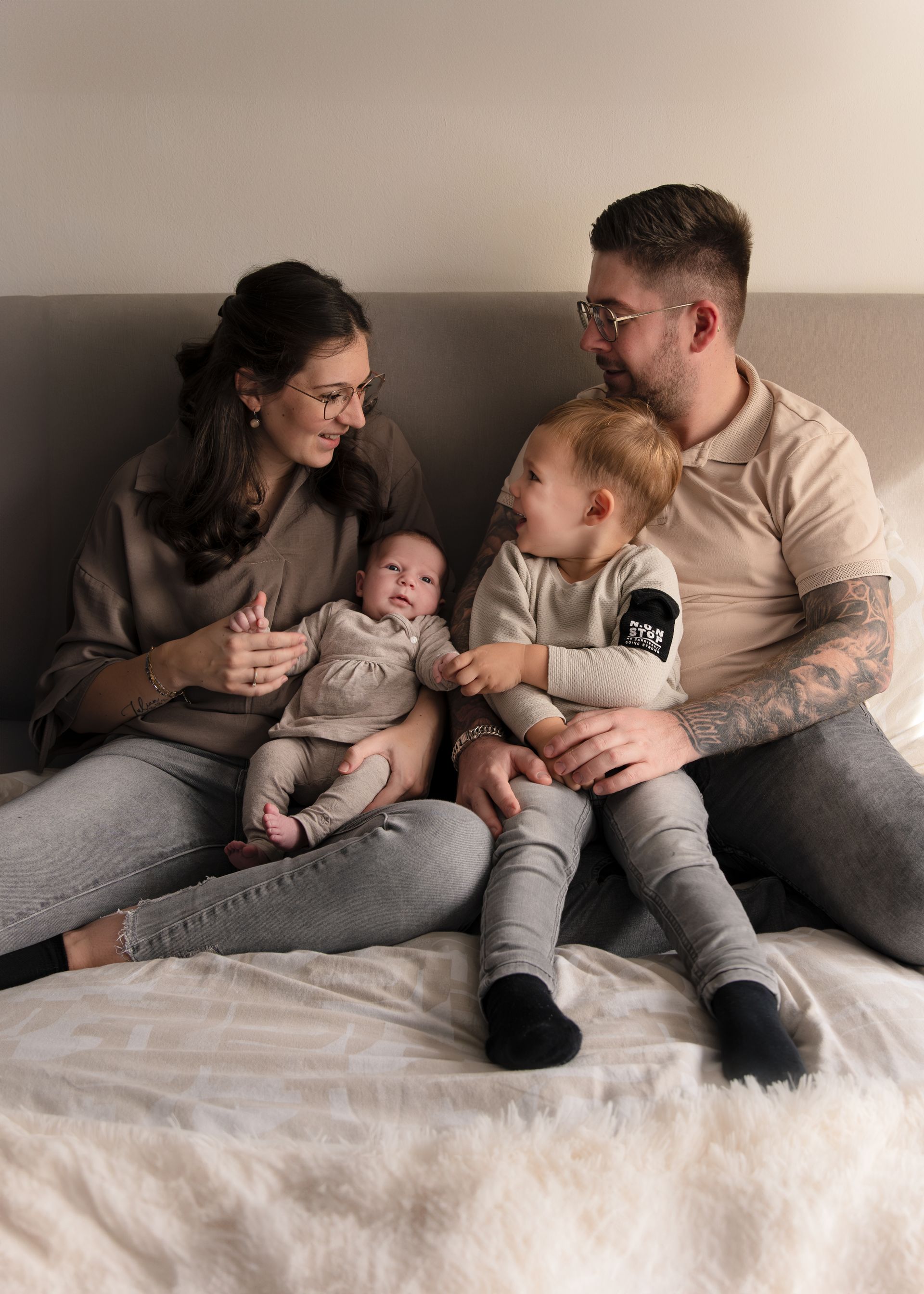 Een gezin zit op een bed met twee baby's.