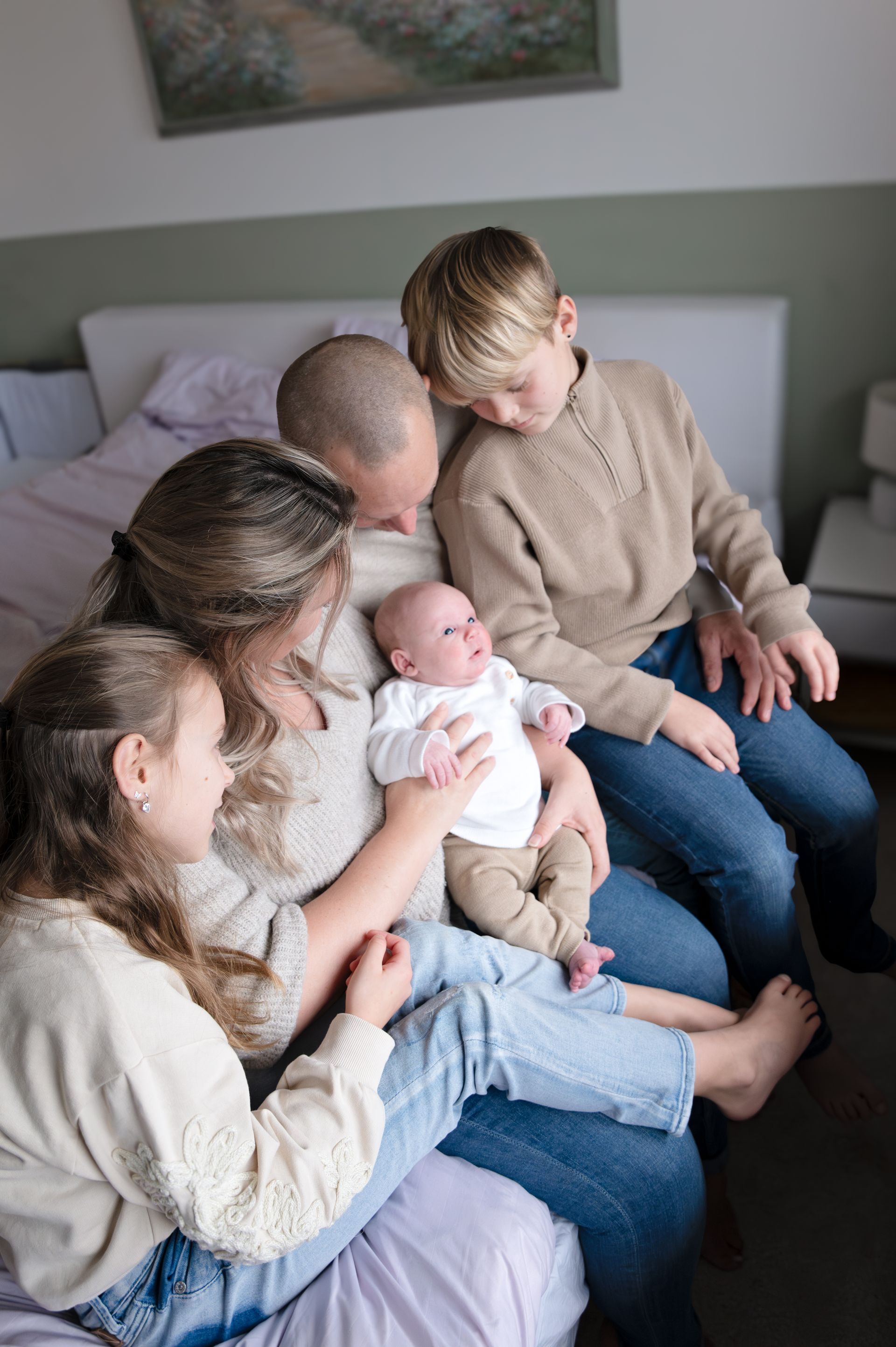 Een gezin zit op een bed met een pasgeboren baby.