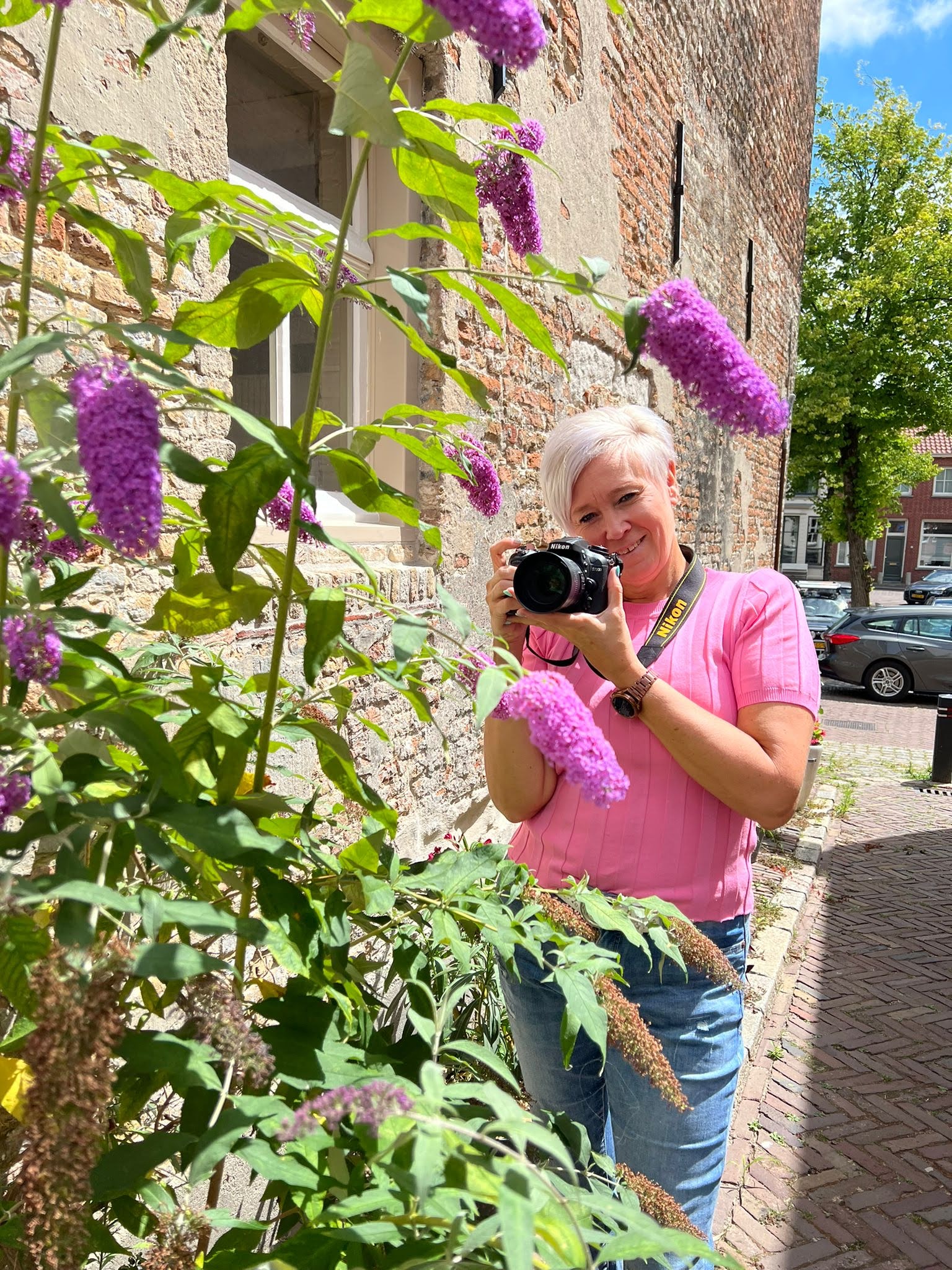 Een vrouw maakt met een camera een foto van paarse bloemen.