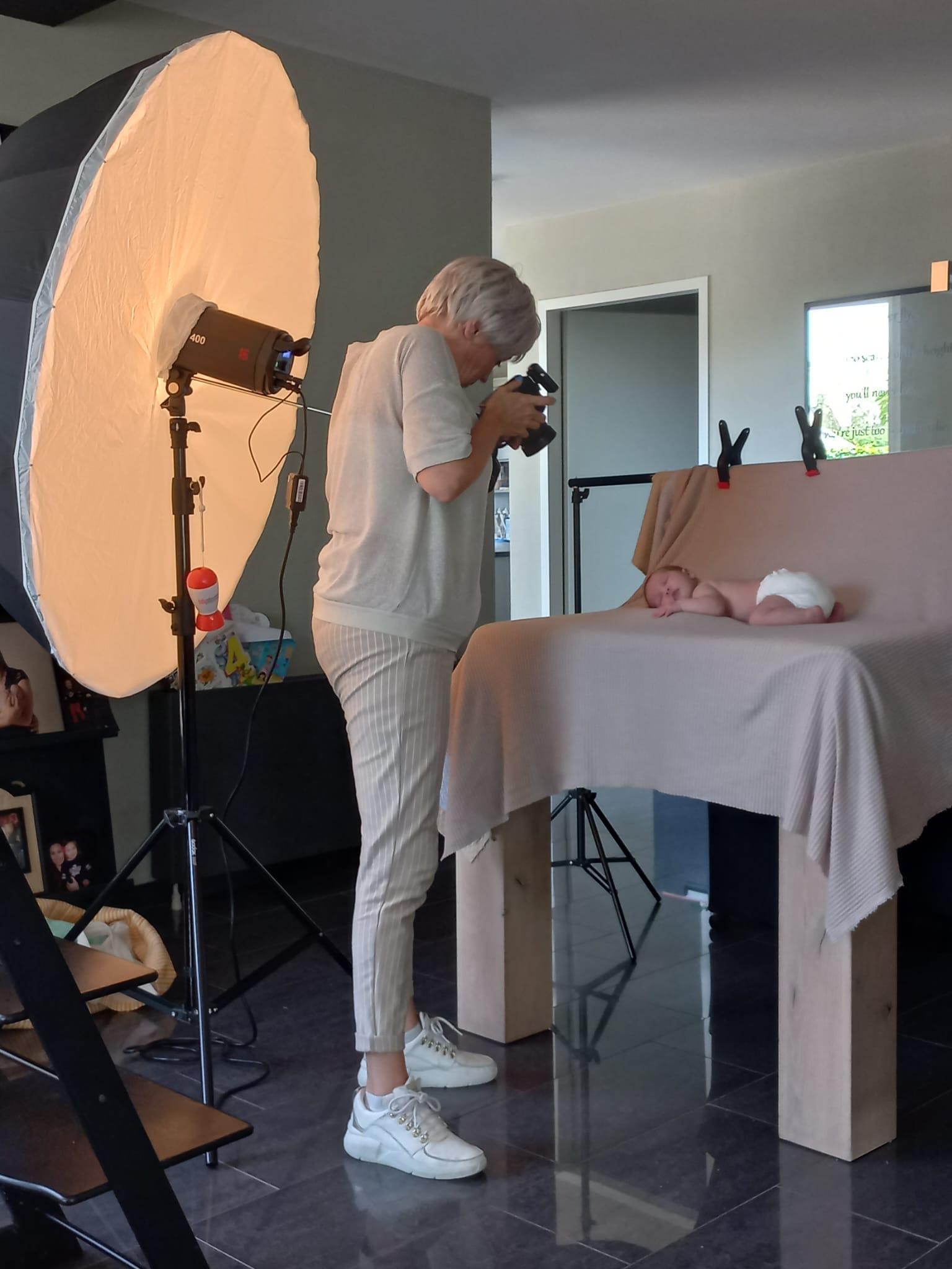 Een man maakt een foto van een baby op een tafel