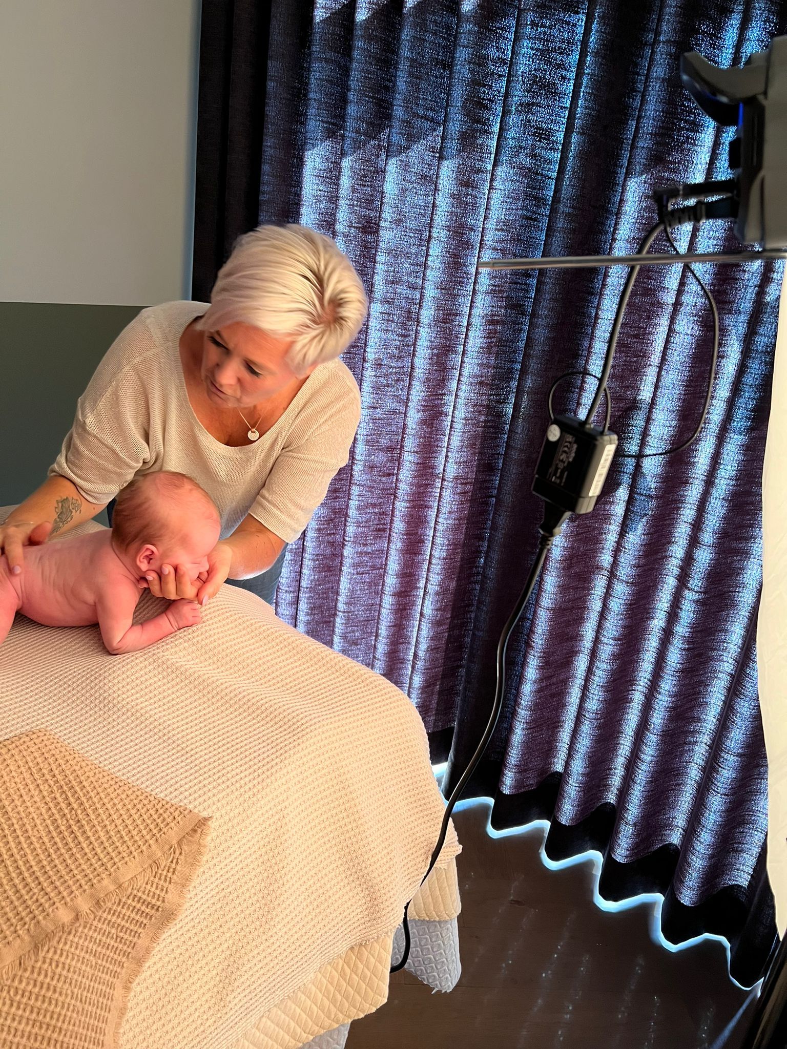 Een vrouw houdt een baby vast op een bed in een kamer.