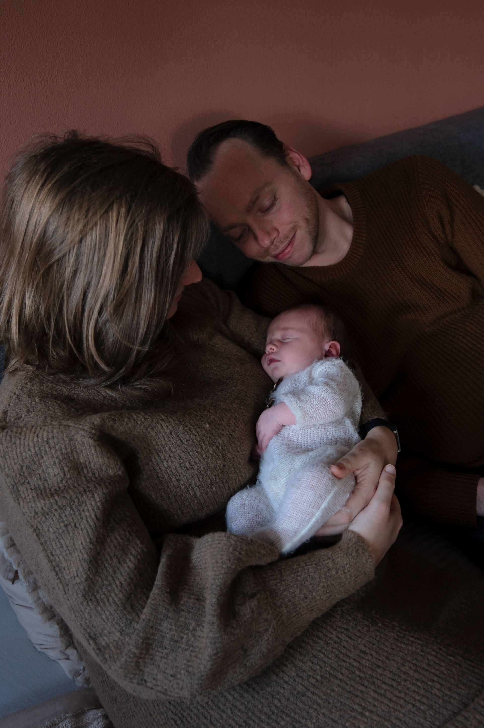 Een man en een vrouw houden een baby in hun armen.