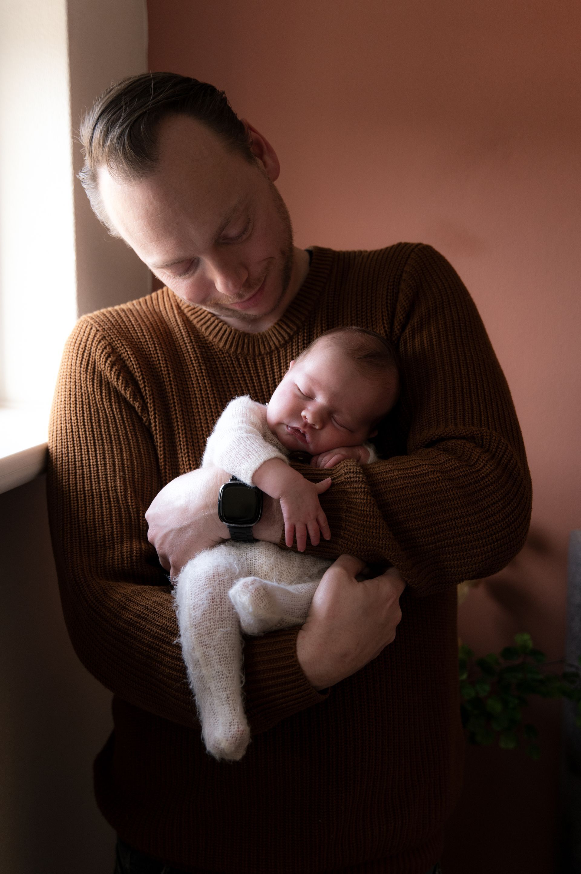 Een man houdt een pasgeboren baby in zijn armen.