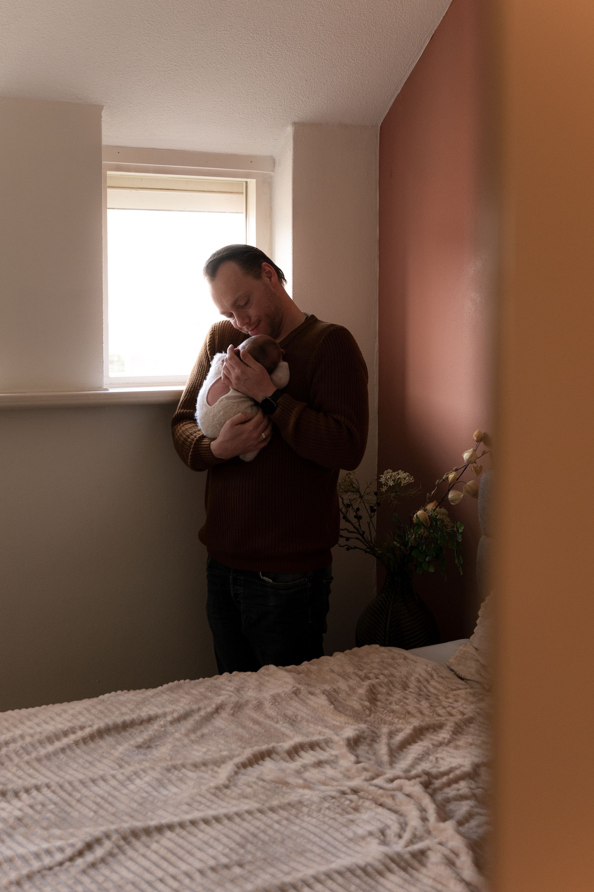 Een man houdt een baby in zijn armen in een slaapkamer.