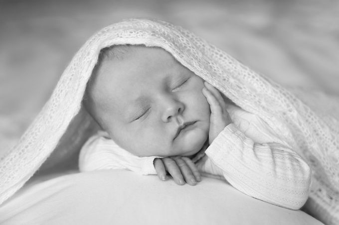 Een pasgeboren baby slaapt op een wit kussen.