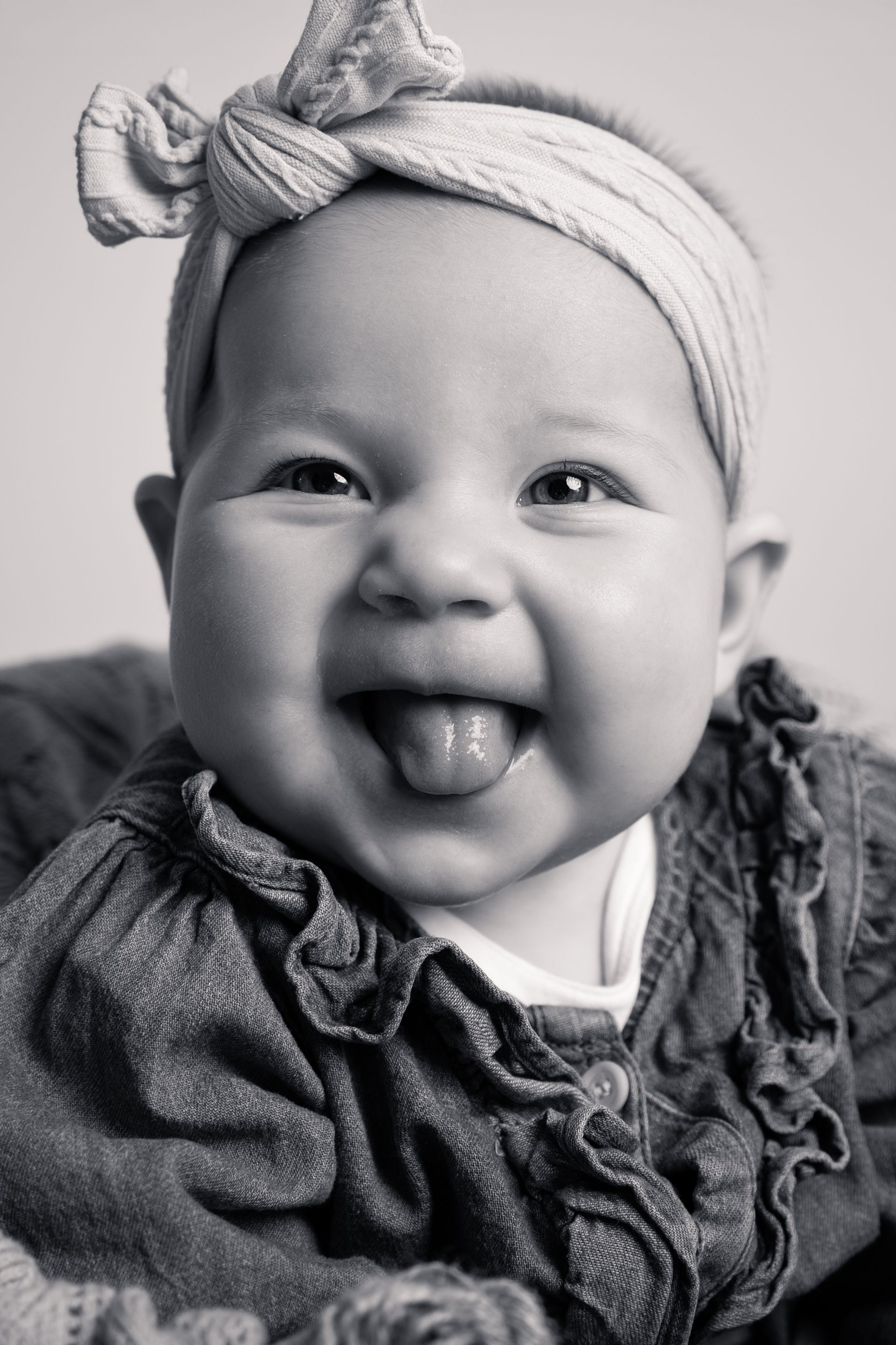 Een zwart-witfoto van een baby die haar tong uitsteekt.