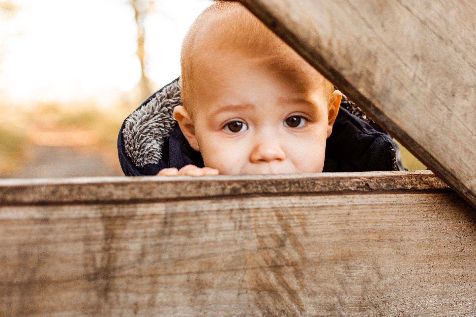 Een baby gluurt over een houten hek.