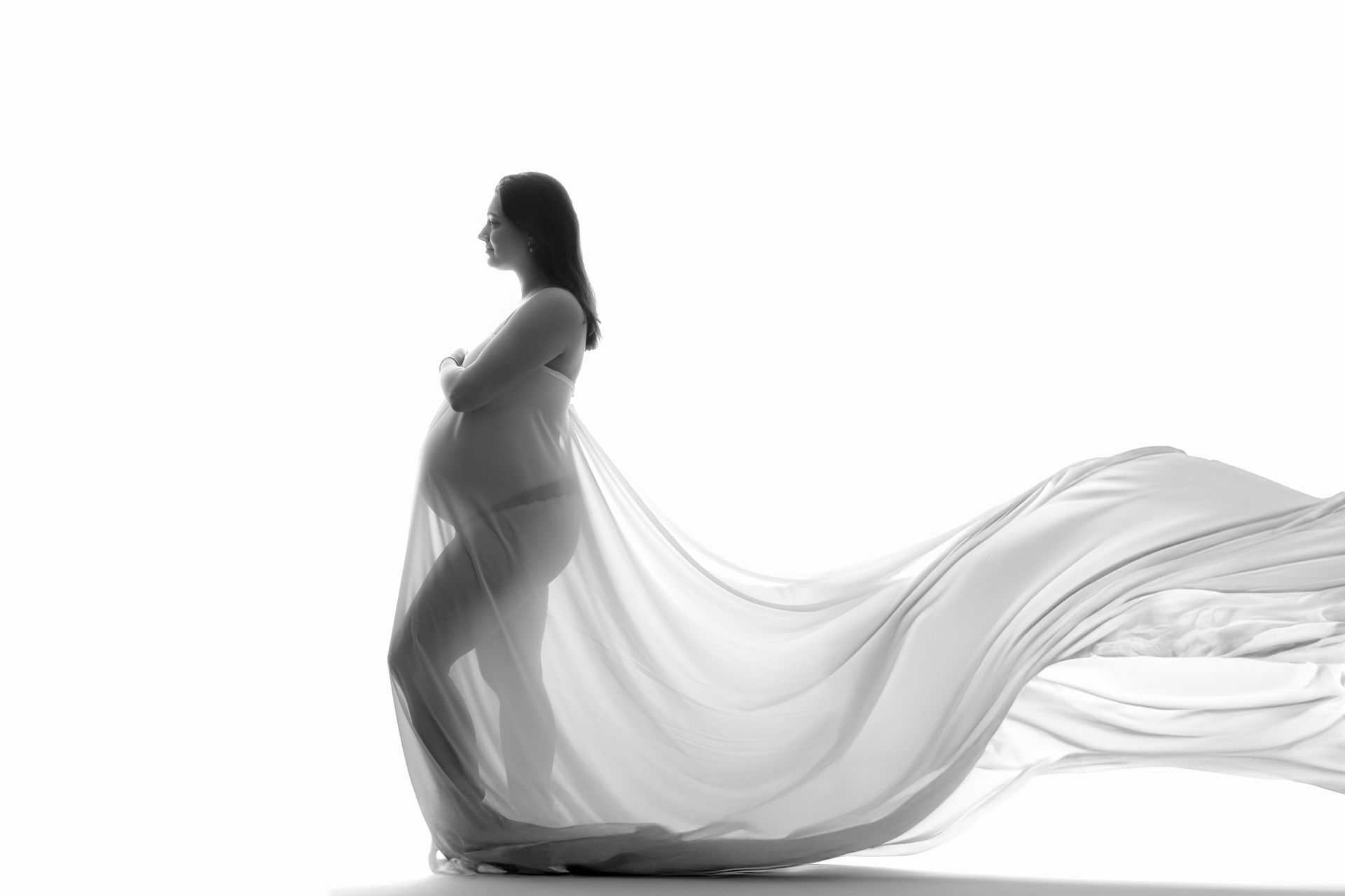 Een zwangere vrouw is gewikkeld in een lange witte doek.