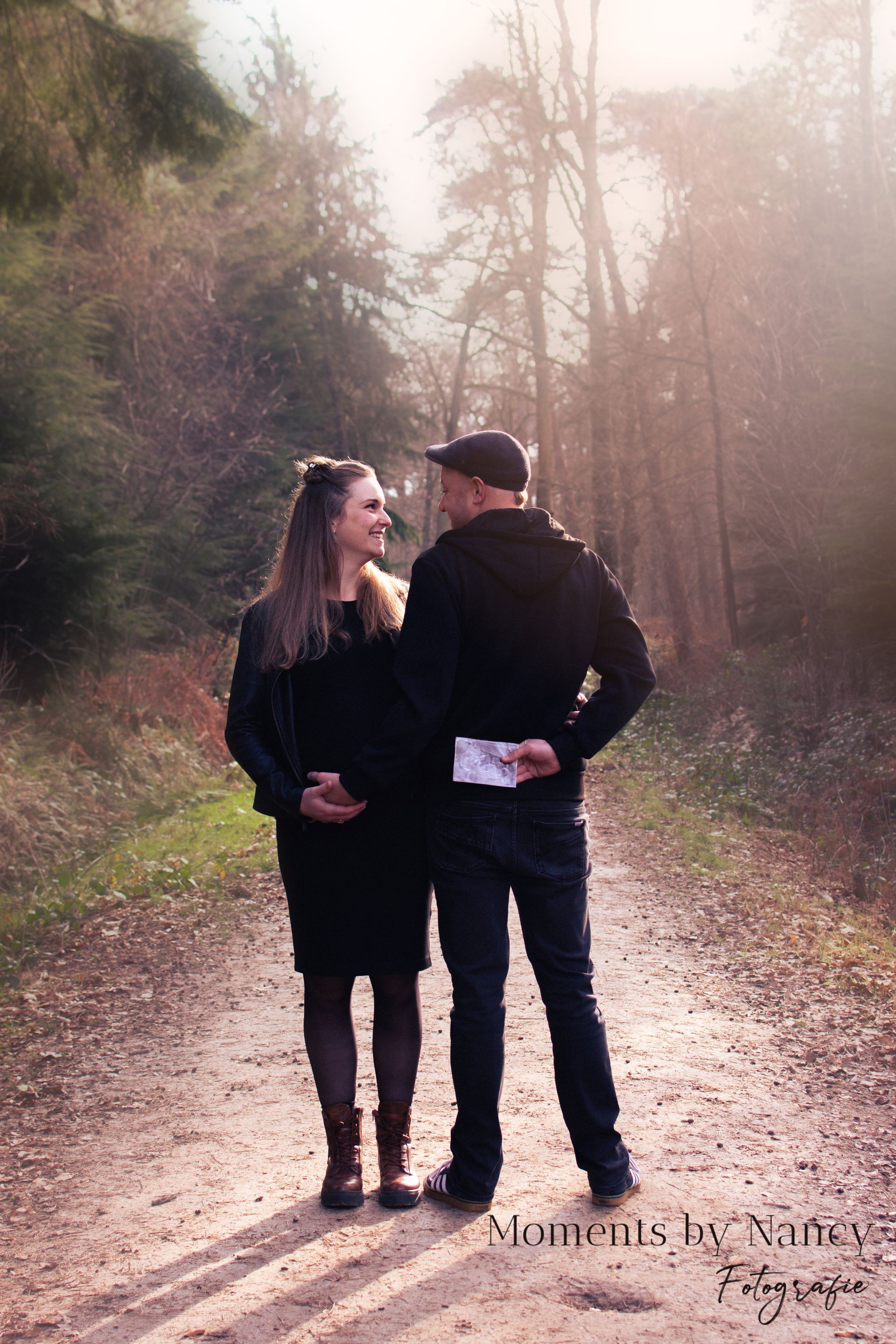 Een man en een zwangere vrouw staan ​​naast elkaar op een onverharde weg.