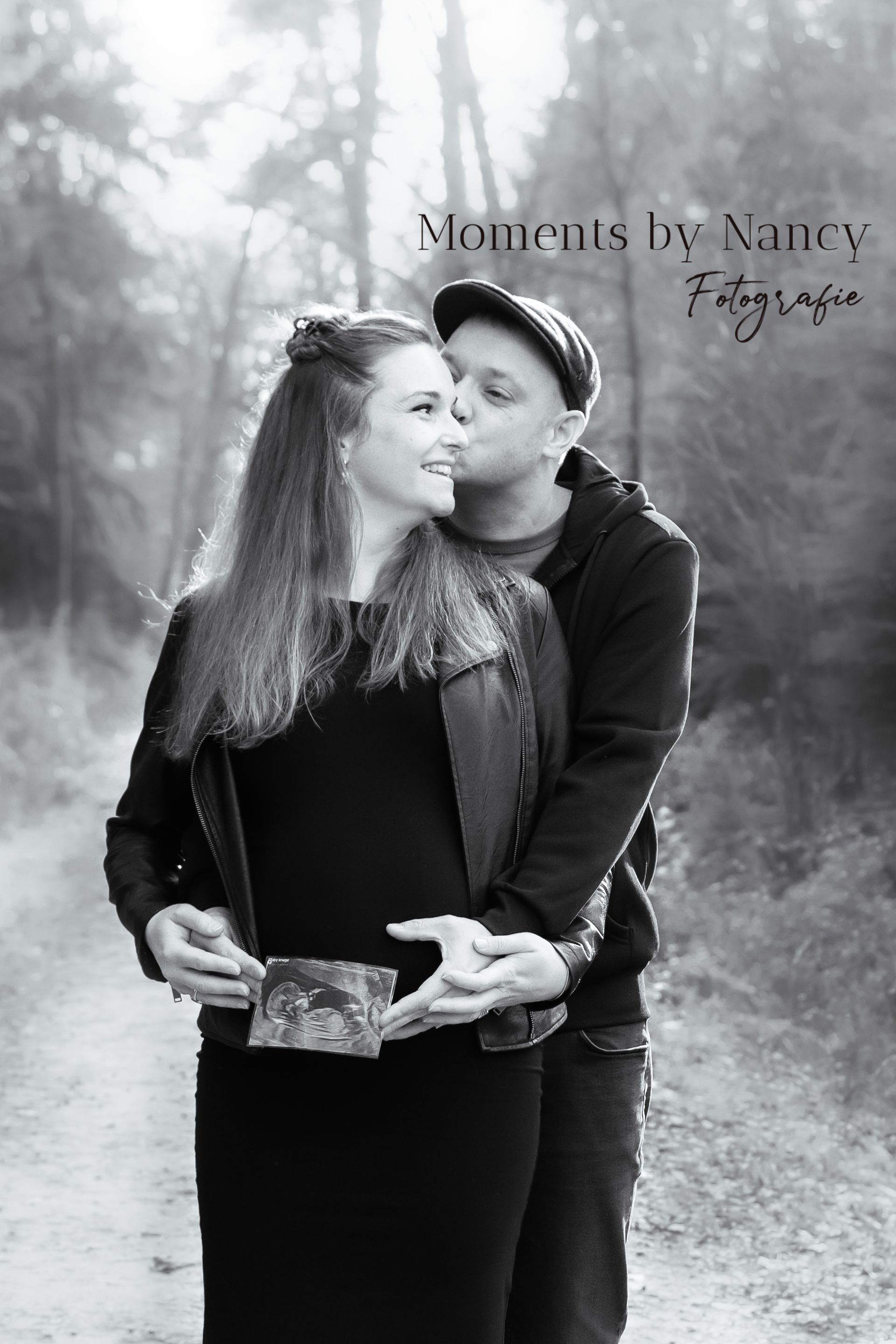 Op een zwart-witfoto kust een man een zwangere vrouw op de wang.