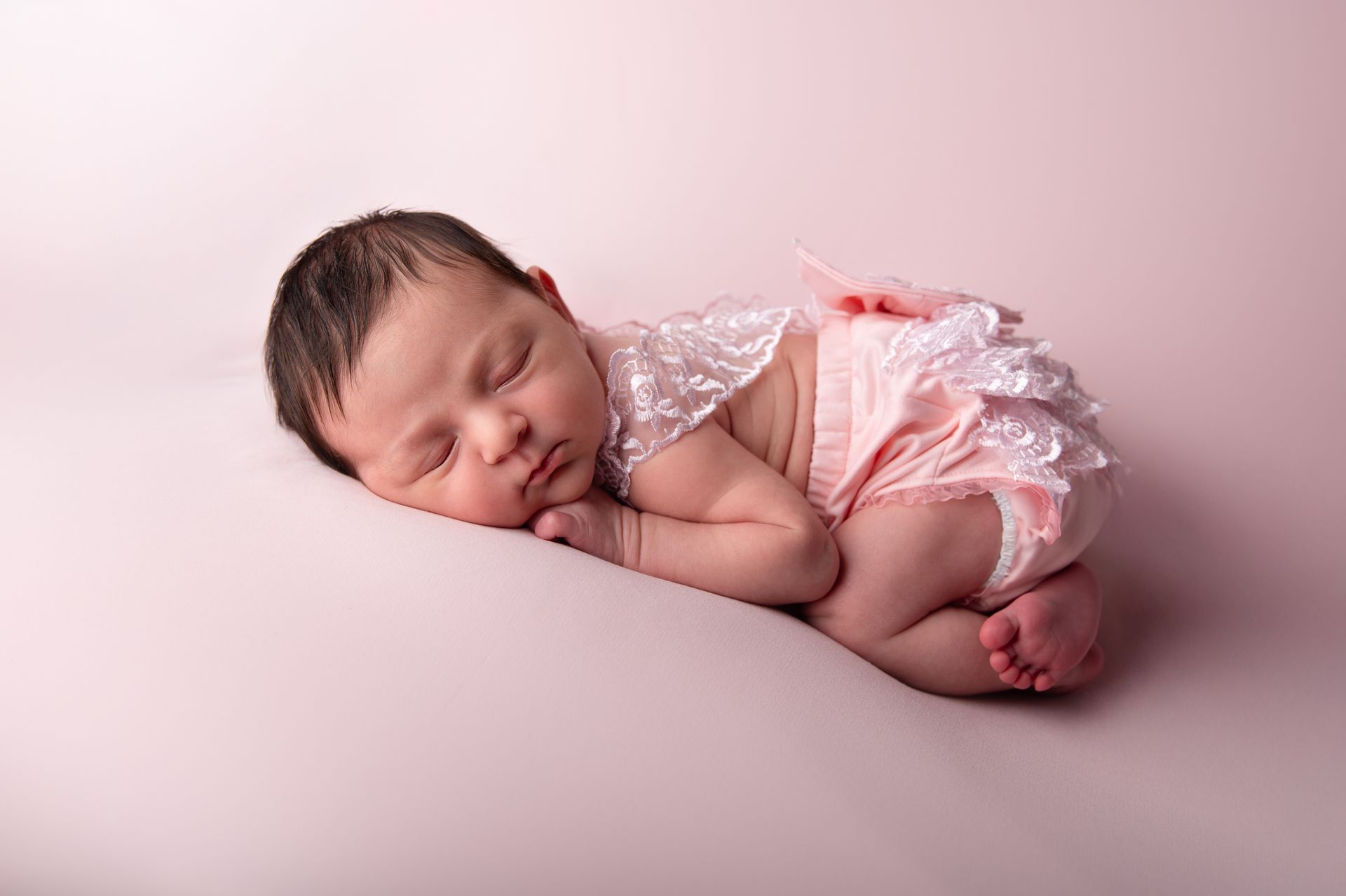 Een pasgeboren meisje slaapt op een roze deken.