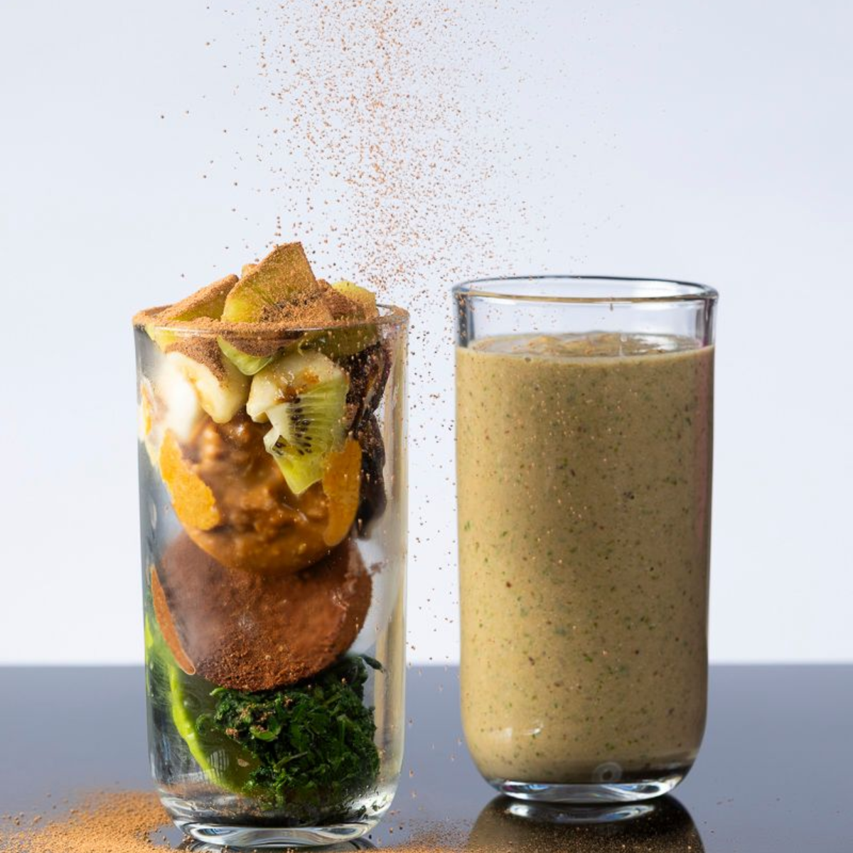 Man laughing, eyes closed, wearing a backward cap and denim jacket, lit by blue and pink light.