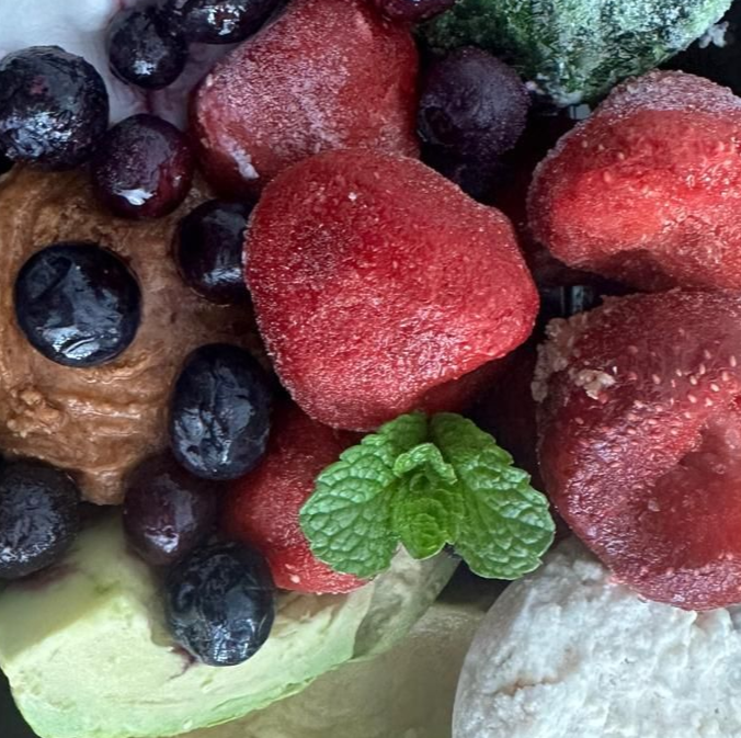 Close-up of frozen strawberries, blueberries, avocado, with mint leaves.