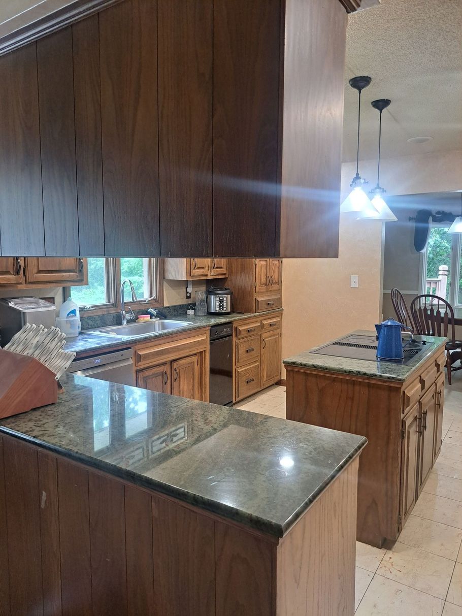 Wooden kitchen with granite countertops. A kitchen island and cabinets are visible.