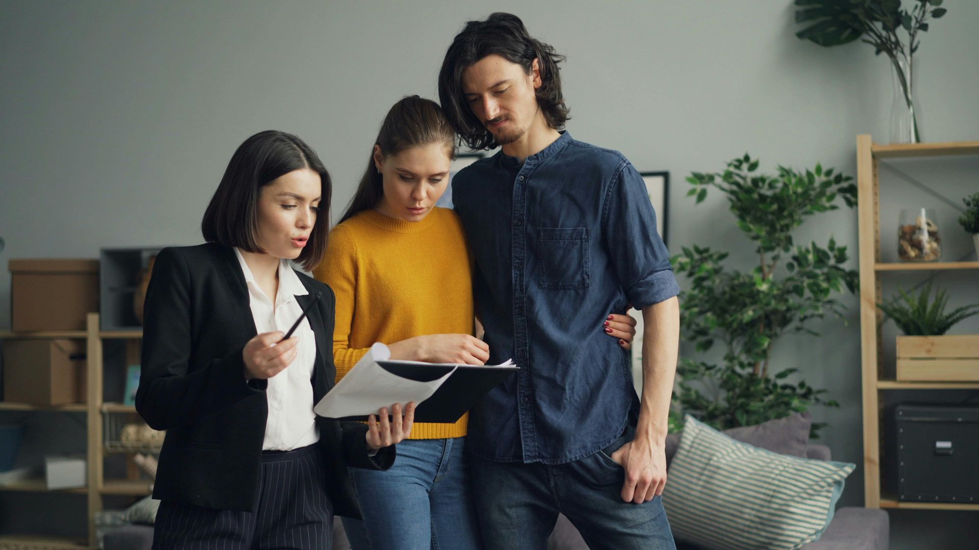 Real estate agent showing paperwork to a couple in a living room.