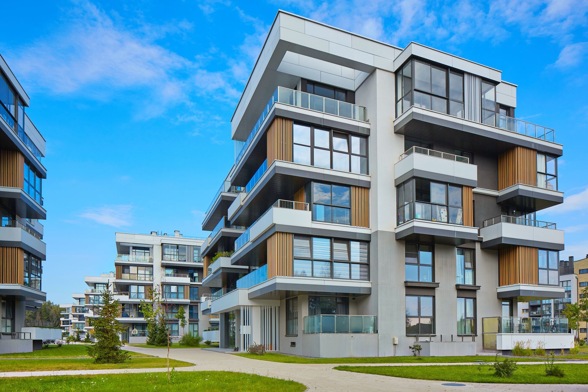 Modern apartment buildings with glass balconies and blue sky.