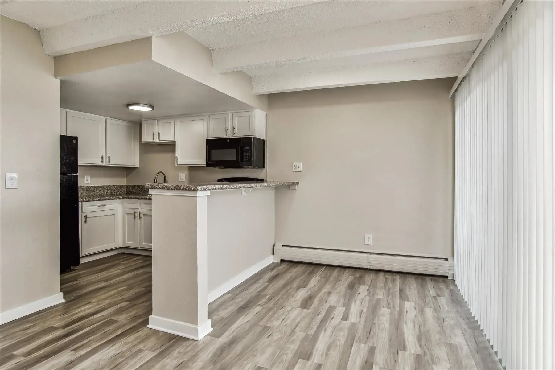 Modern kitchen with white cabinets, granite countertops, and a breakfast bar.