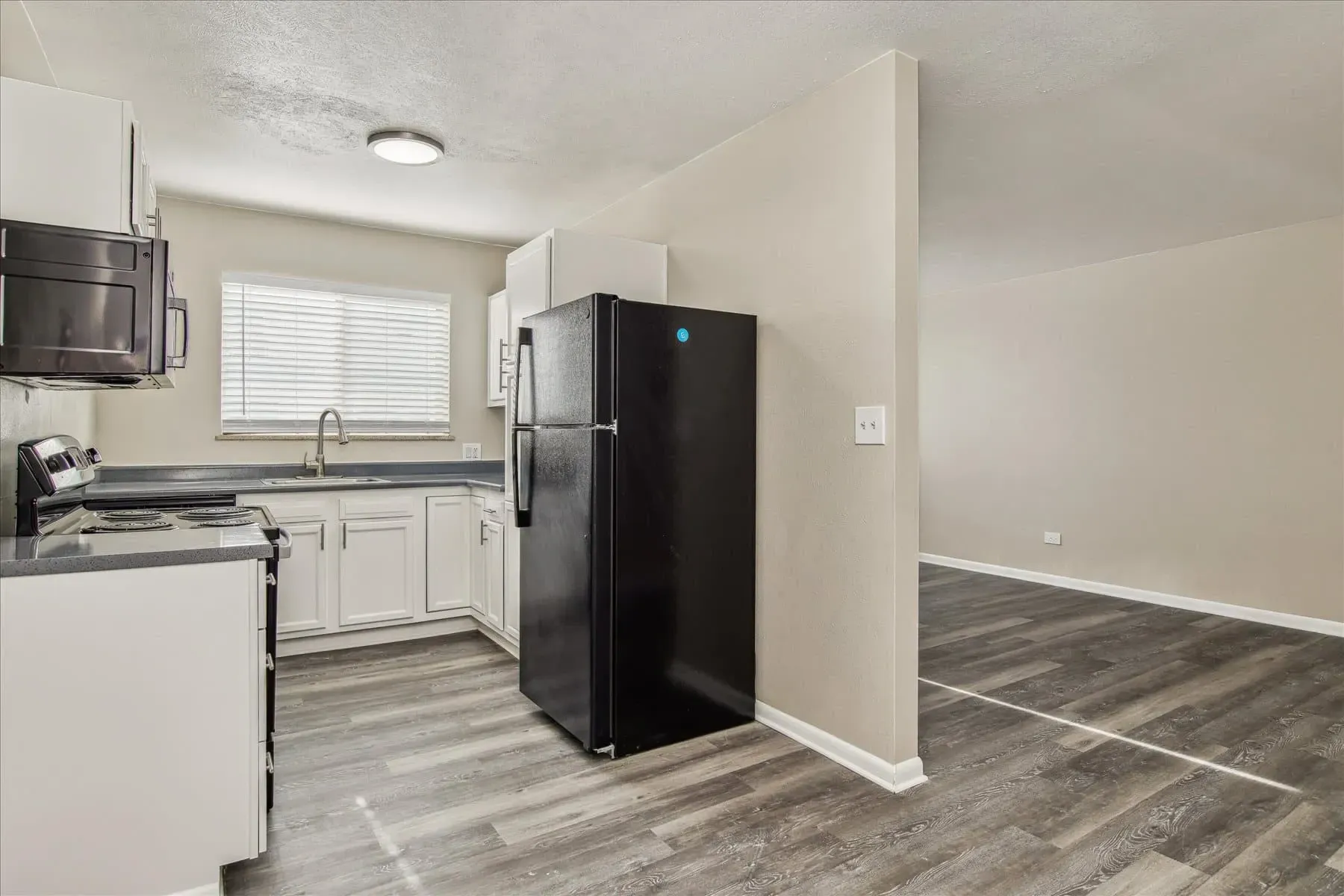 Kitchen with white cabinets, black refrigerator, and stovetop.