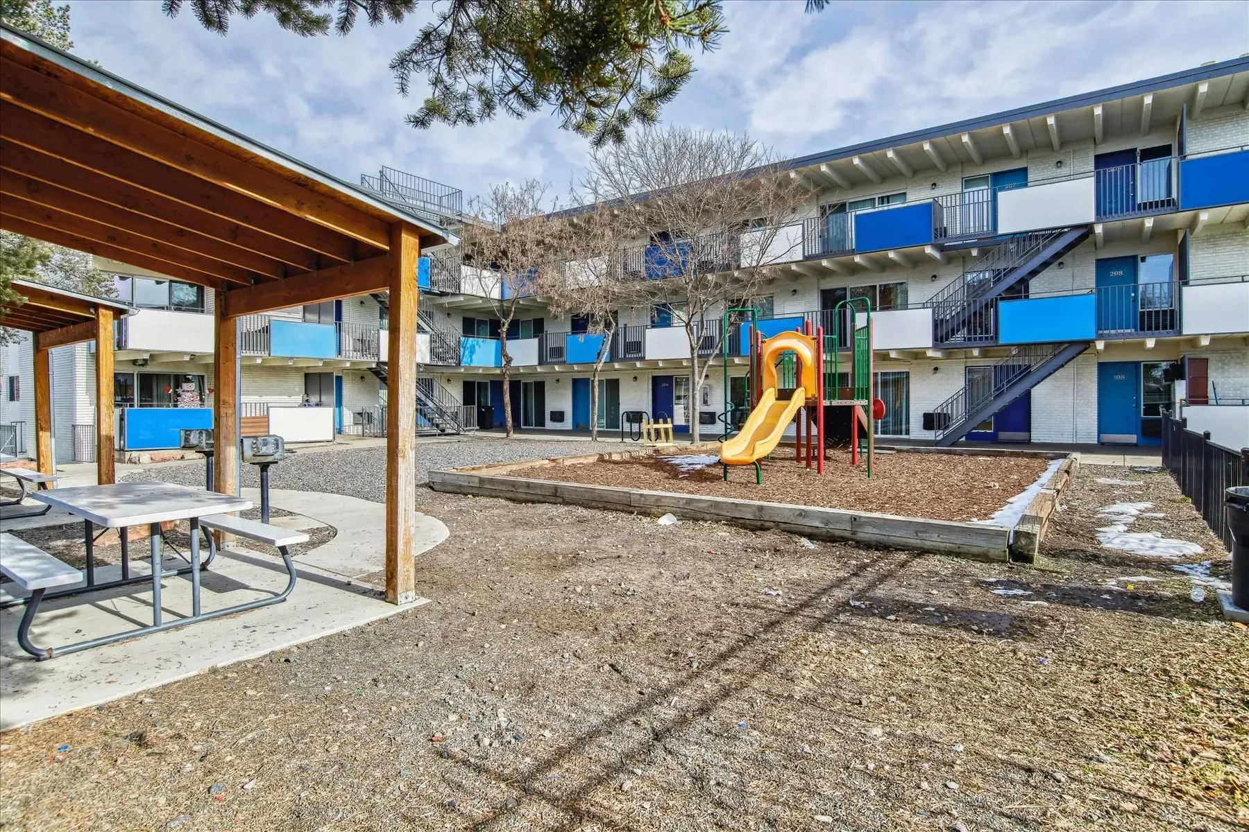 Apartment courtyard with a playground, picnic table, and grill.