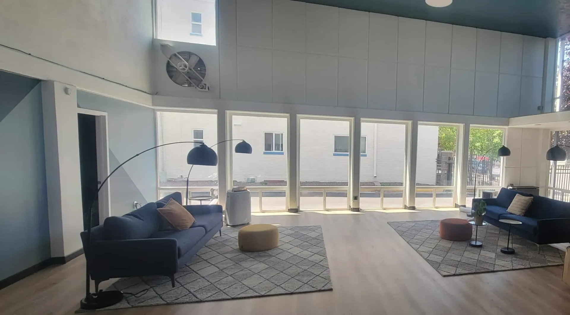 Modern lounge area with blue sofas, arc lamps, and large windows.