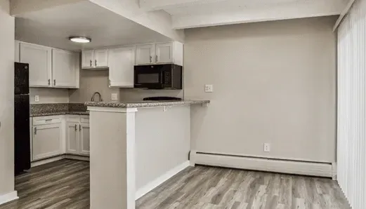 Kitchen with white cabinets, granite countertops, black appliances, and a breakfast bar.