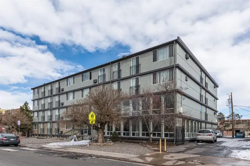 Exterior of a multi-story apartment building with balconies and large windows.