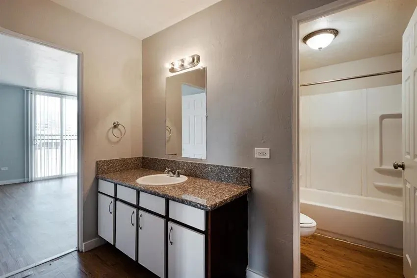 Bathroom vanity with granite countertop and sink, tub-shower combo, and toilet.