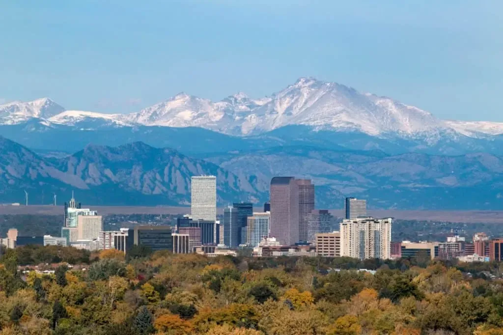 Denver skyline with snow-capped mountains in the background.