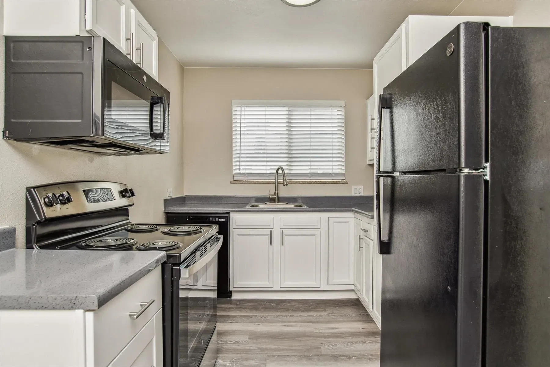Modern kitchen with black appliances and white cabinets.