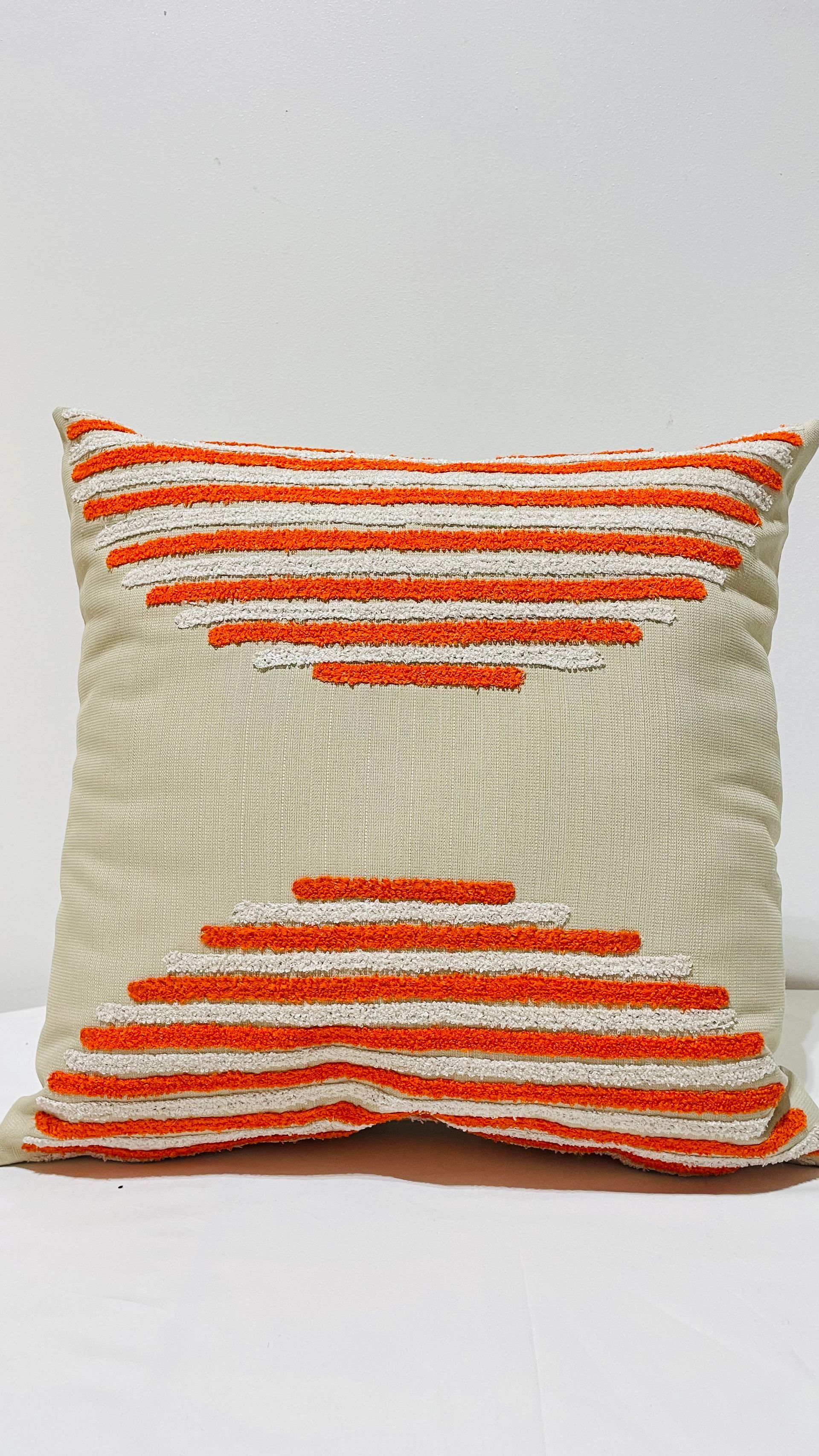 Un coussin rayé blanc et orange est posé sur une table blanche.