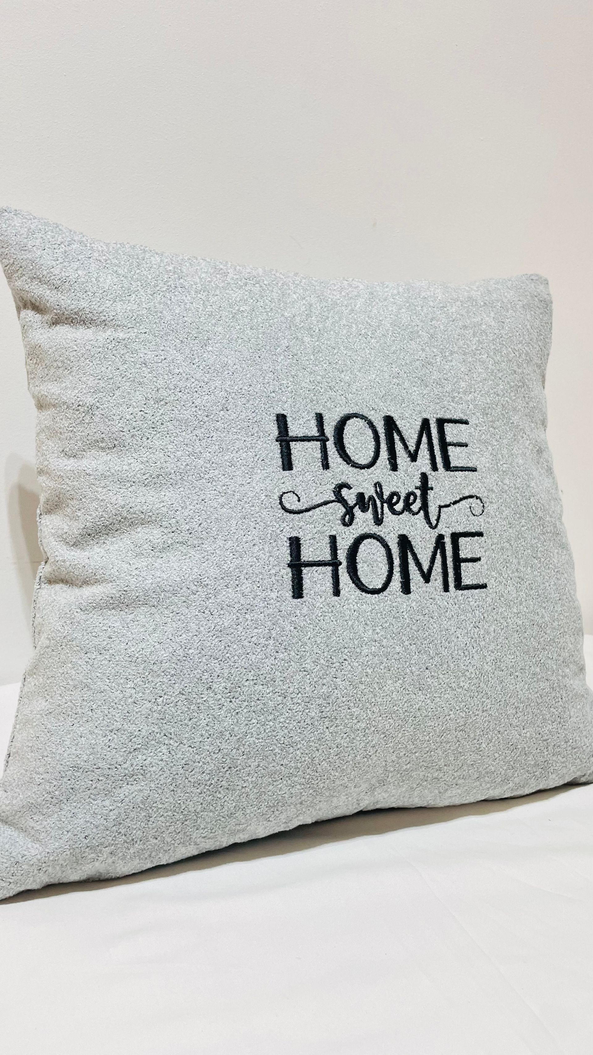 Un oreiller avec les mots « home sweet home » brodés dessus est posé sur une table.