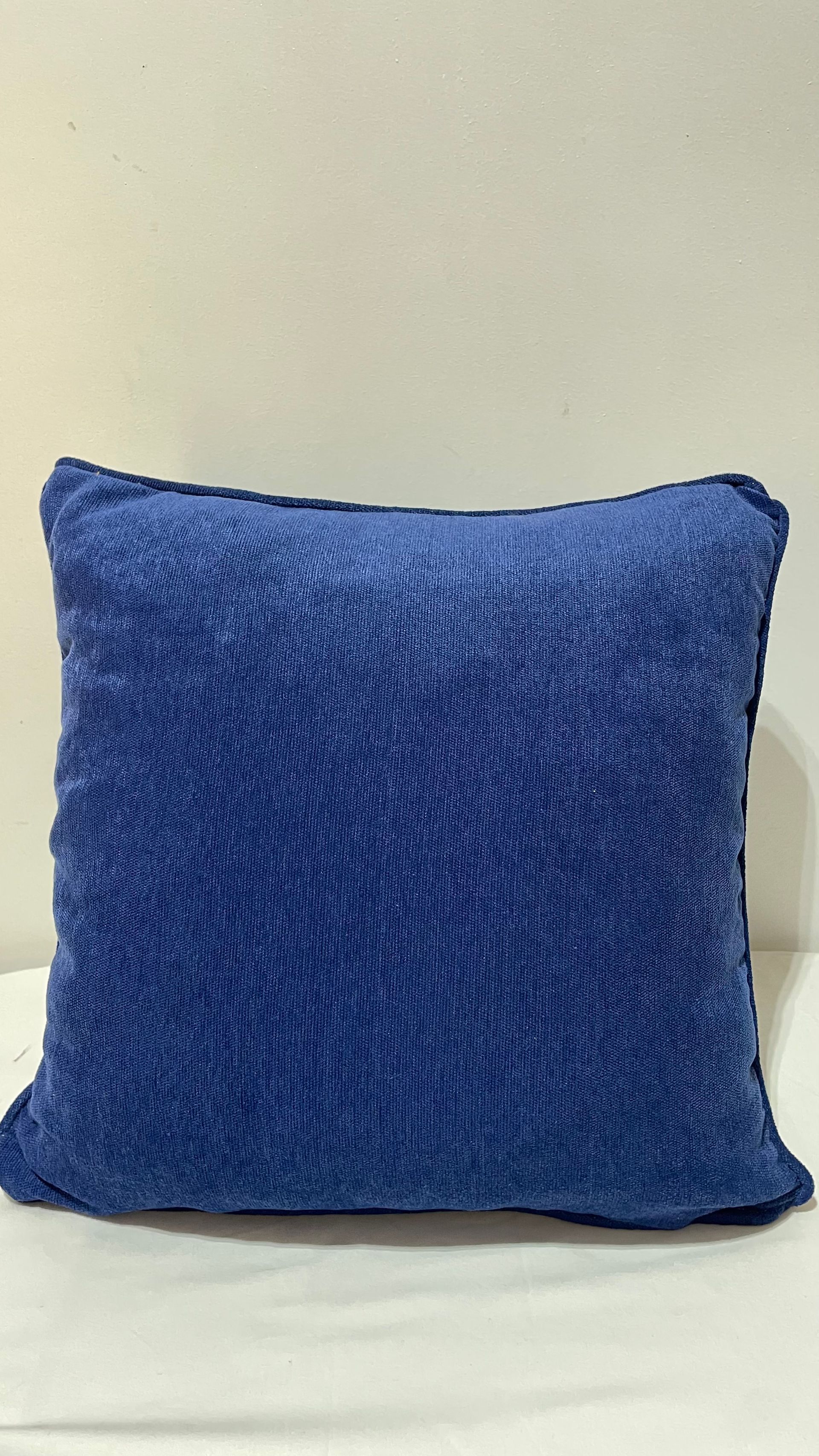 Un oreiller bleu est posé sur une table blanche.