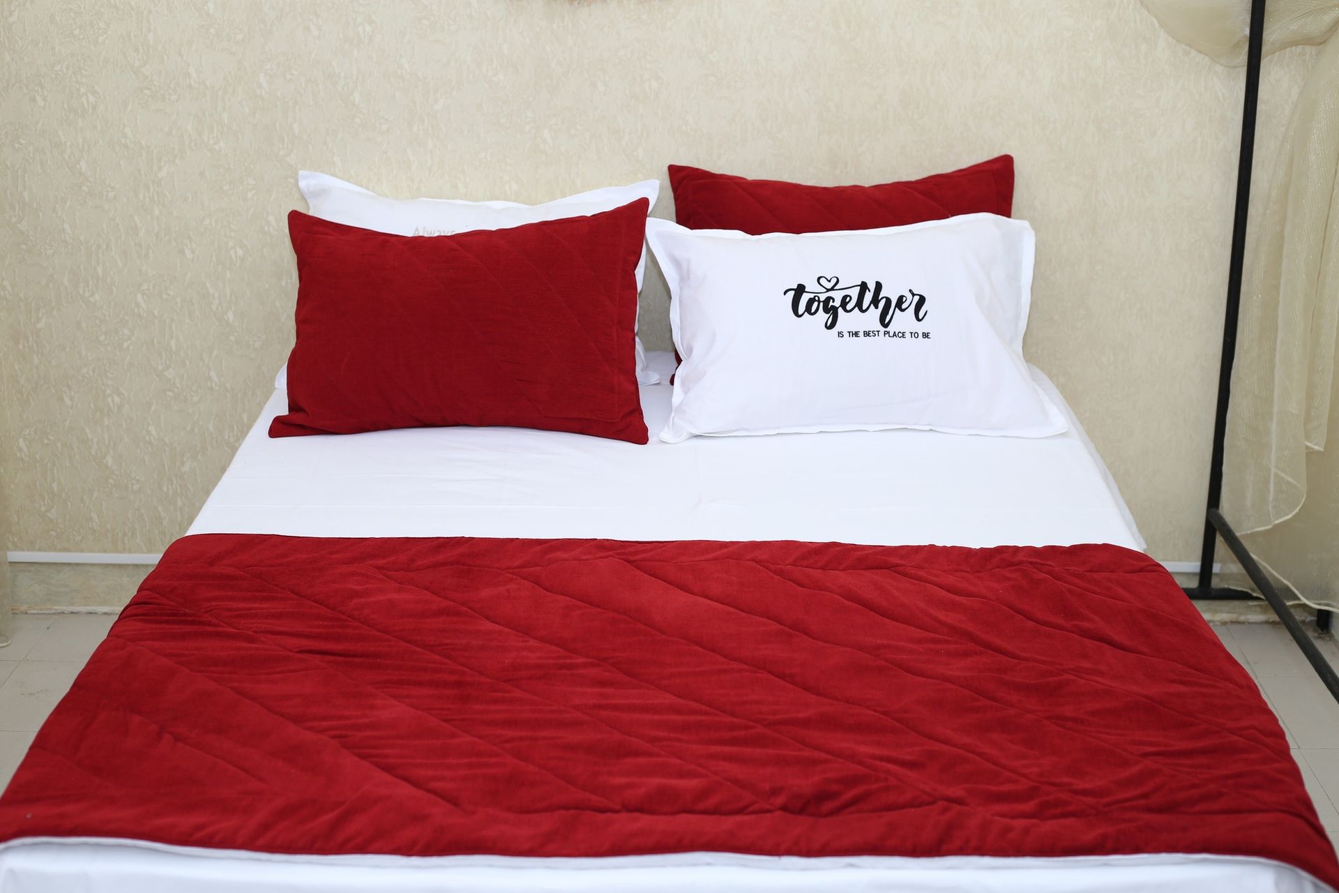 Un lit avec une couette rouge et des oreillers qui disent ensemble