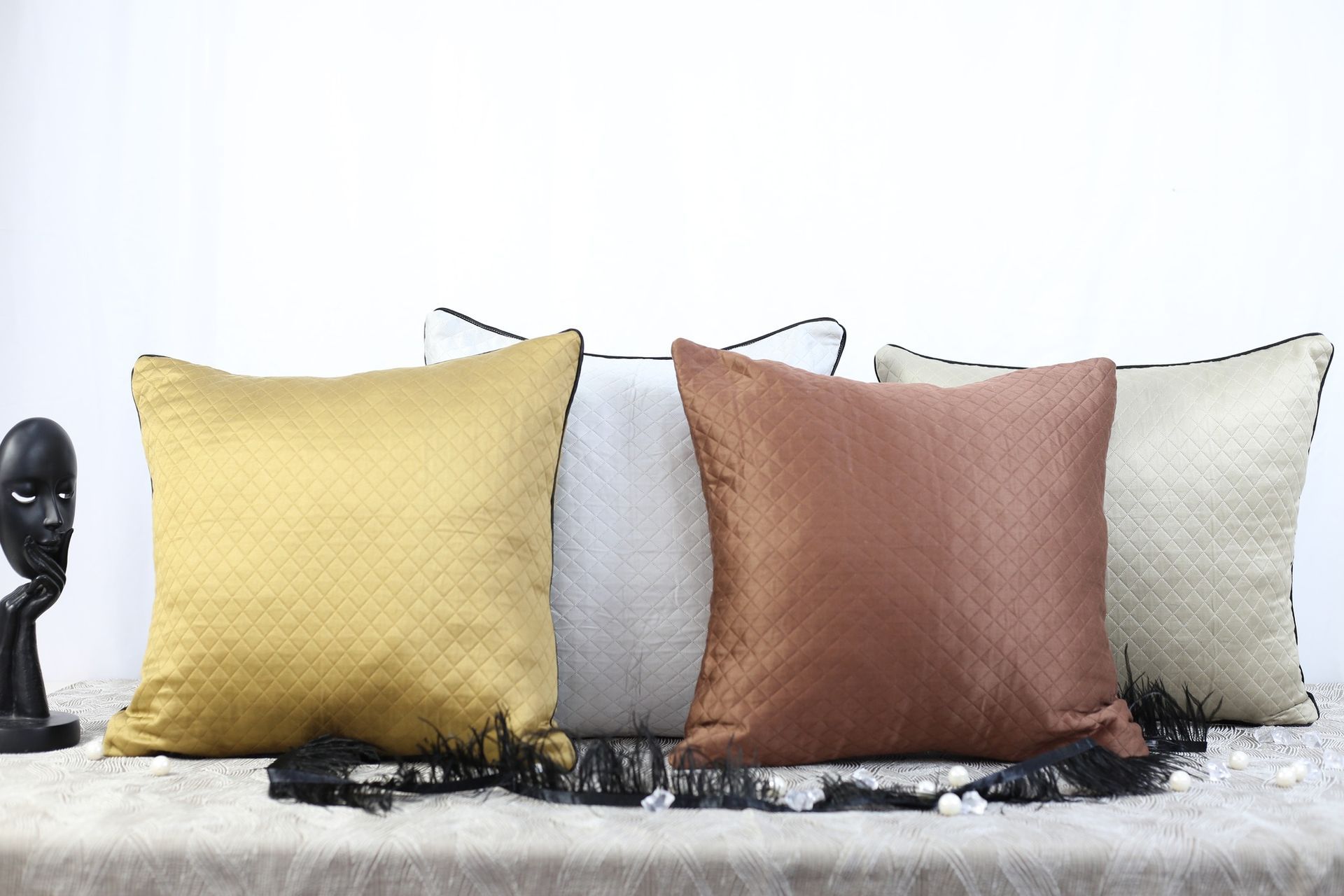 Trois oreillers sont posés sur un canapé à côté d'une statue.