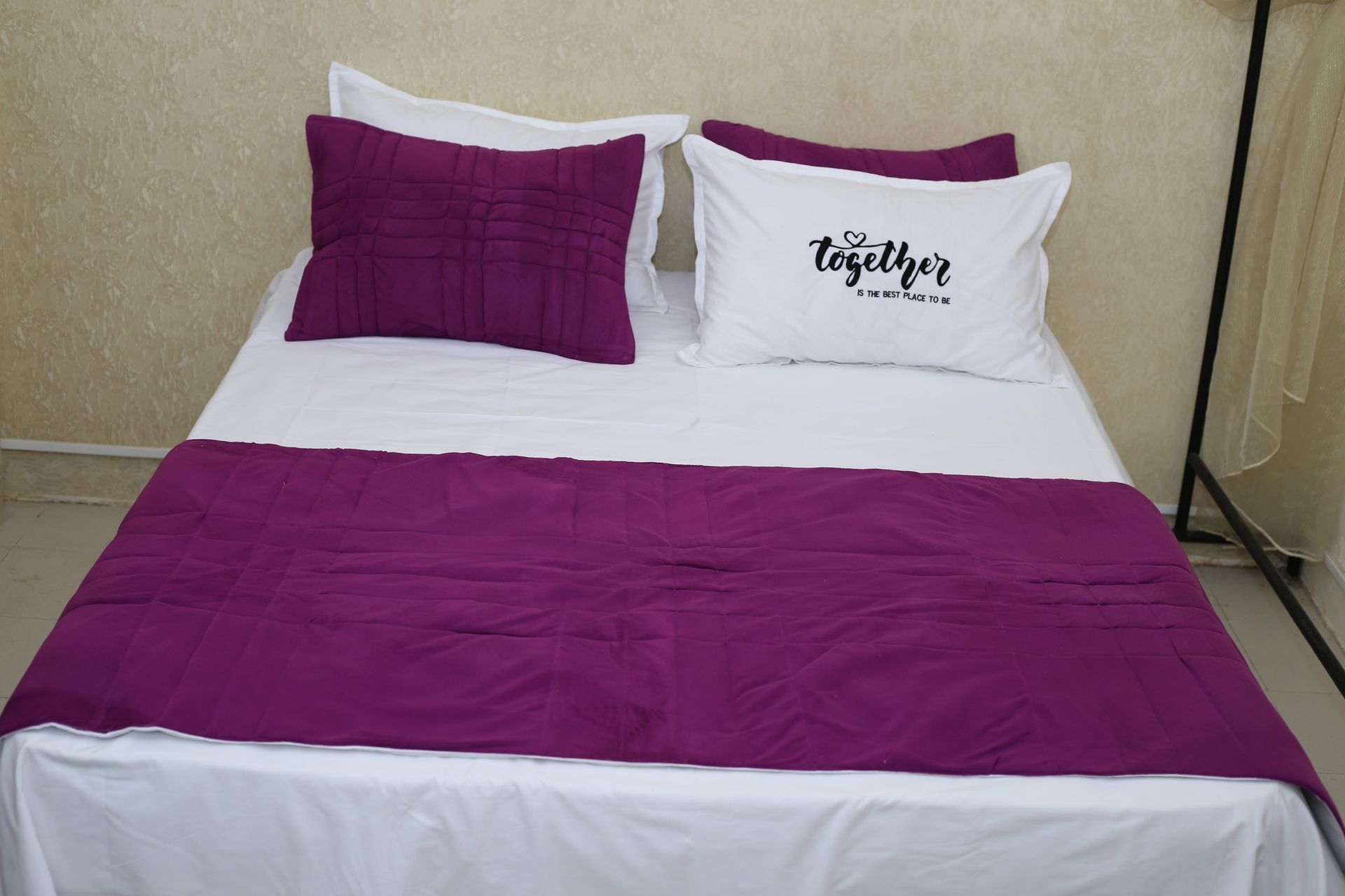 Un lit avec des oreillers violets et blancs et une couverture violette