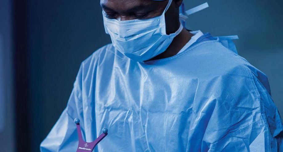 A surgeon wearing a mask and gown is operating on a patient.